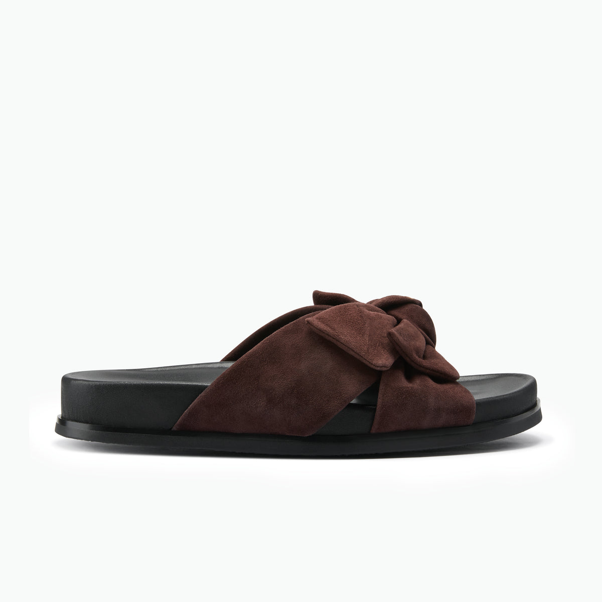 A single dark brown suede slide sandal with a knotted bow detail across the strap, set against a solid white background.