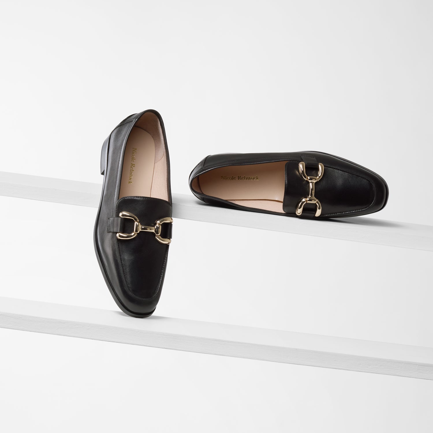 Alisa black leather loafer with chunky gold buckle and black sole on planks showing all sides