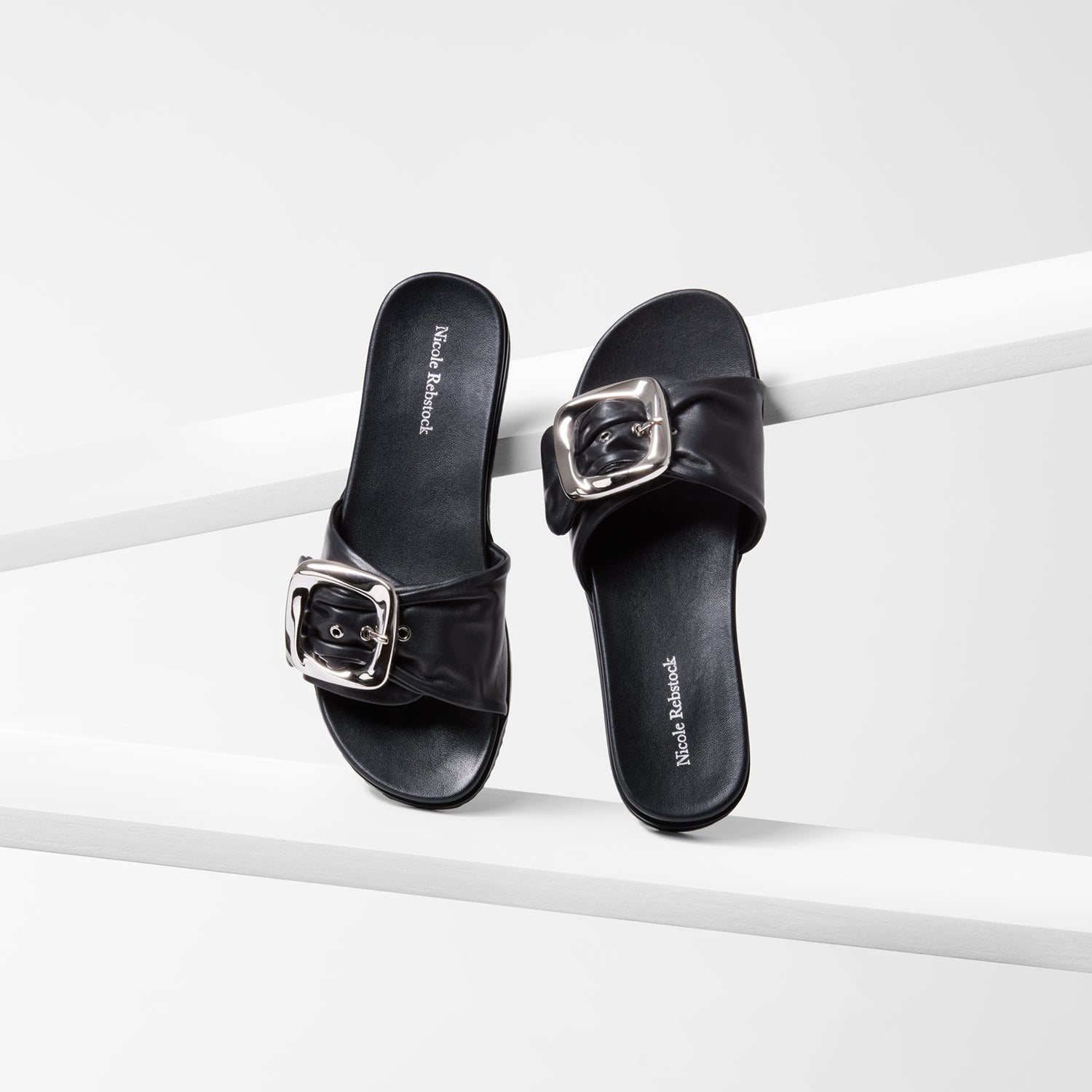 Black sandals with silver buckles on a white background