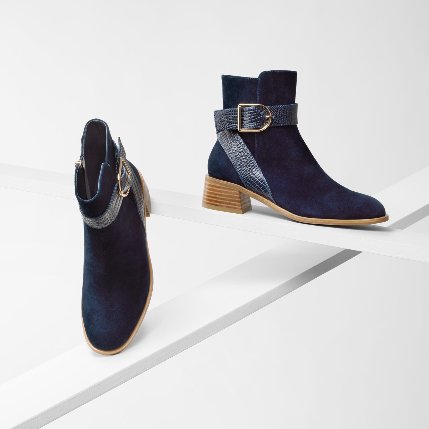 Bologna navy suede ankle boots with stacked leather heel on planks showing all sides.