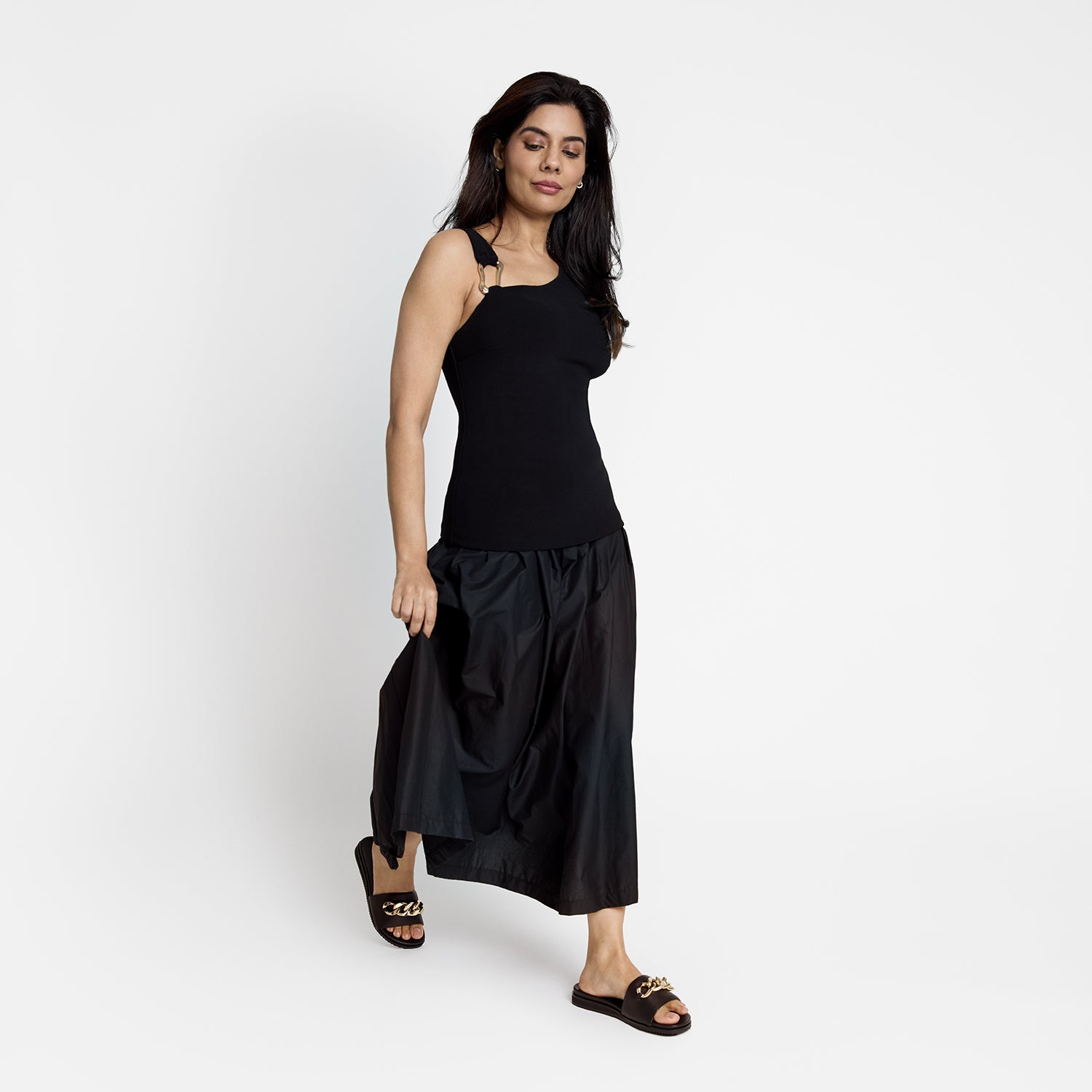 Model wearing black slide sandal called Bowie. They have a black leather upper.