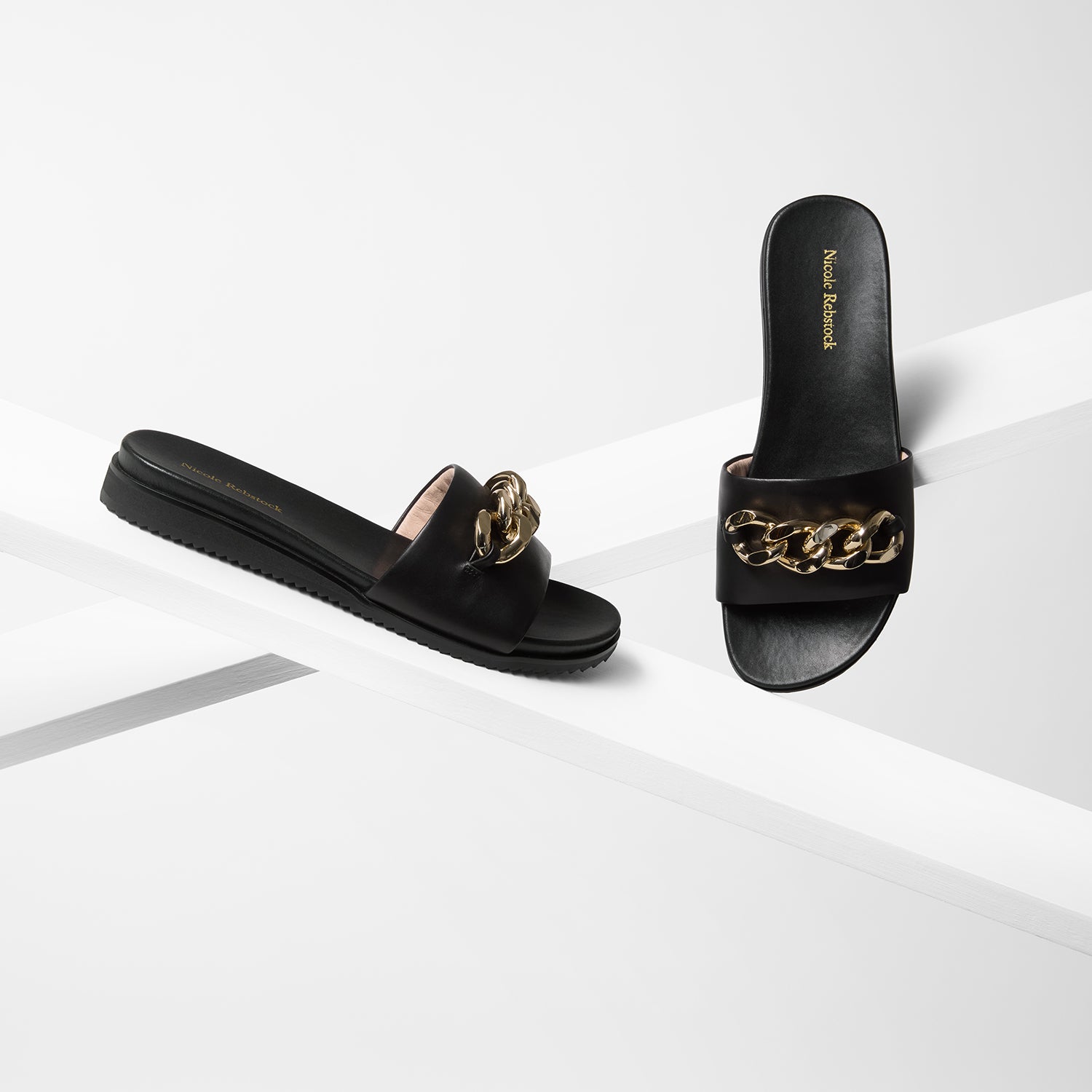Bowie sandal on planks showing all angles. The slide has a EVA outsole and gold metal chain detail.