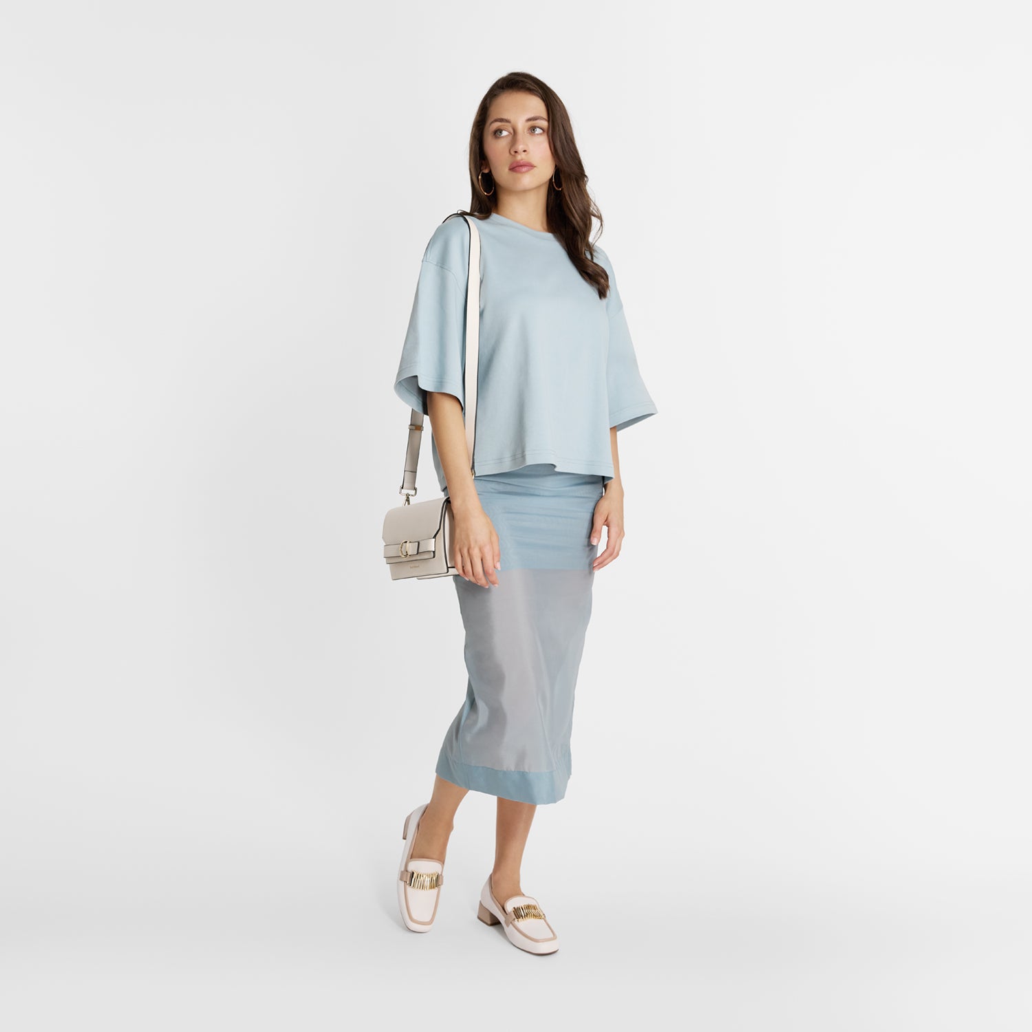 Model wearing Nicole Rebstock Brooks Loafer in cream leather with nude leather trims and gold metal buckle.