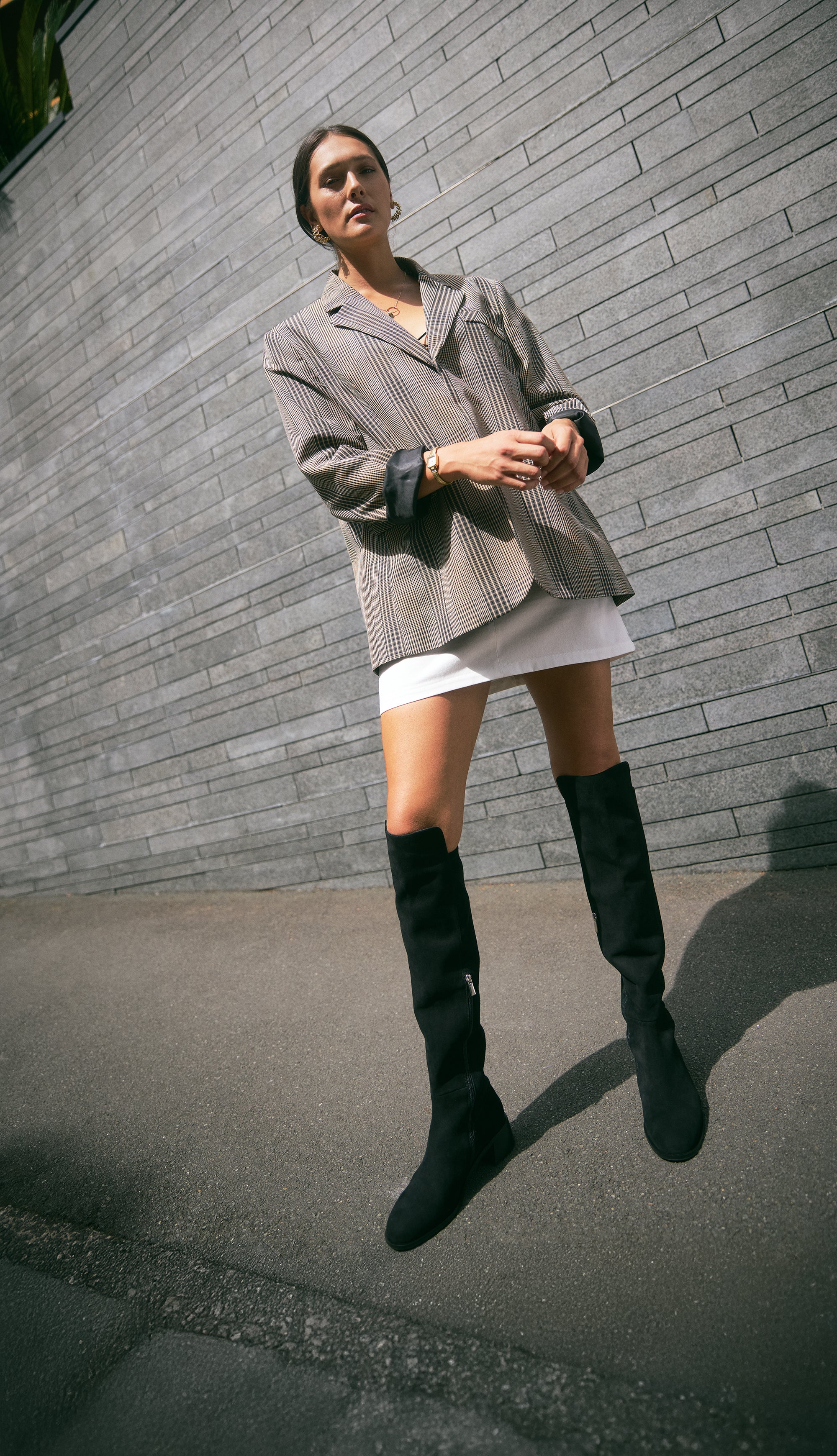 Brussels black suede long boot worn by female model. The shoes feature a low block flat heel and silver zips.