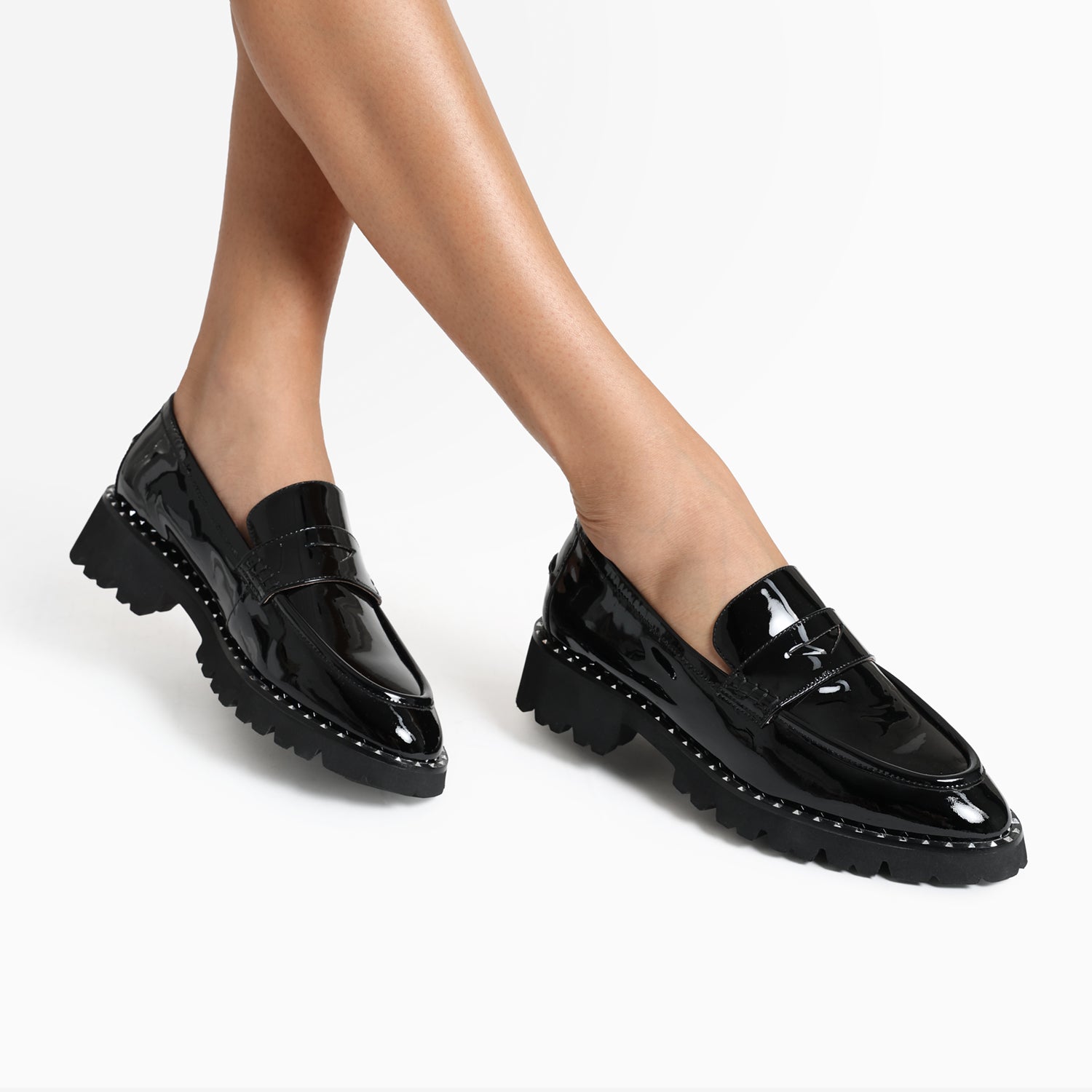 Close up picture of Czech Loafer in black patent worn by woman. The loafer has chunky soles, an almond or pointed toe and silver stud details.