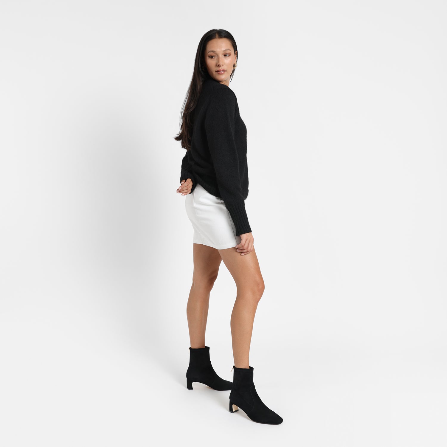 Demi black suede on model wearing a black jumper and a white mini skirt.