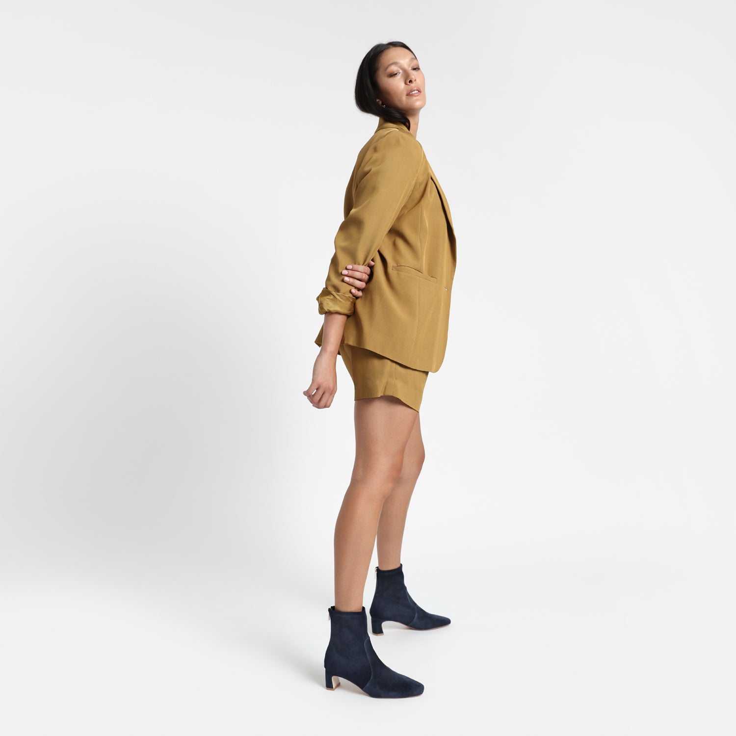 Demi navy suede ankle boot on model wearing a mustard coloured suit.