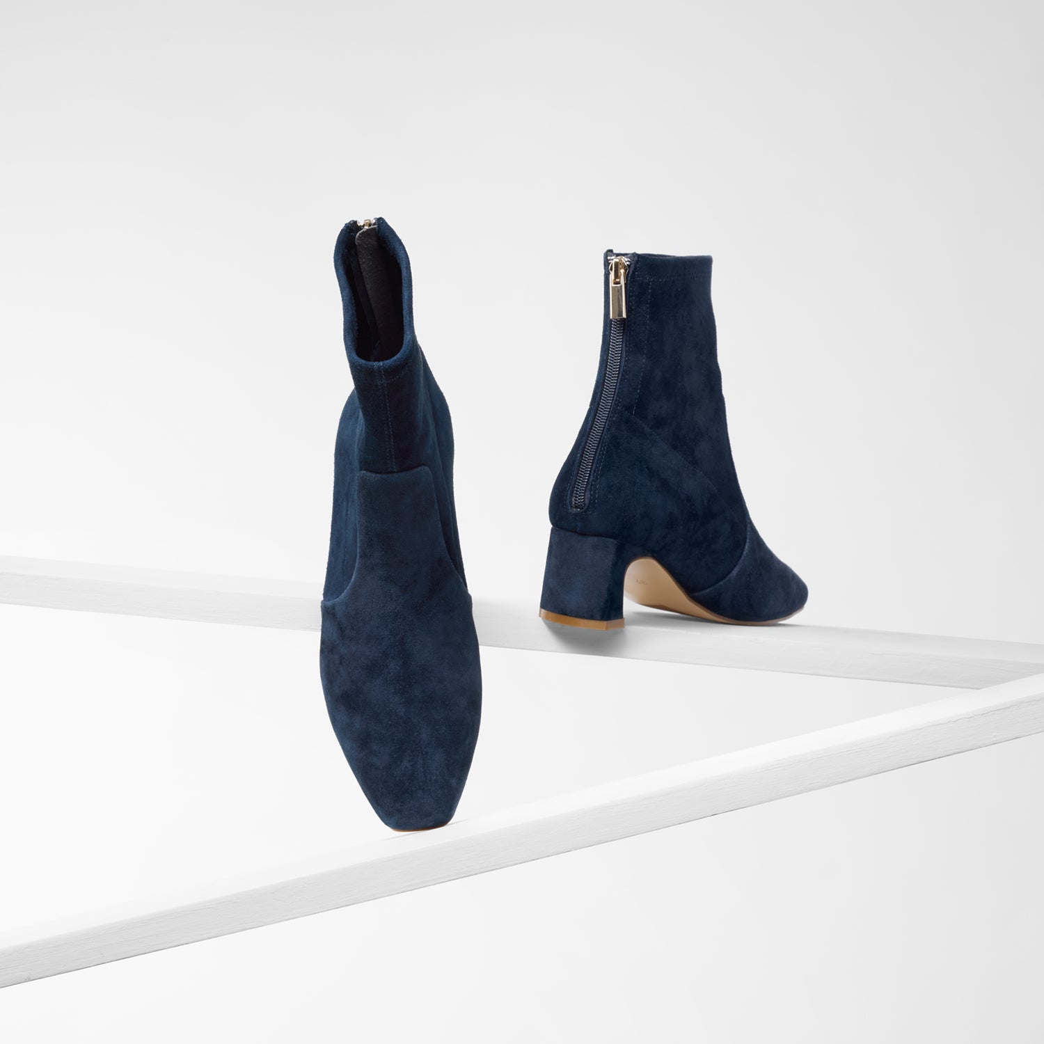 Demi navy suede ankle boot with back zip on planks showing all sides.