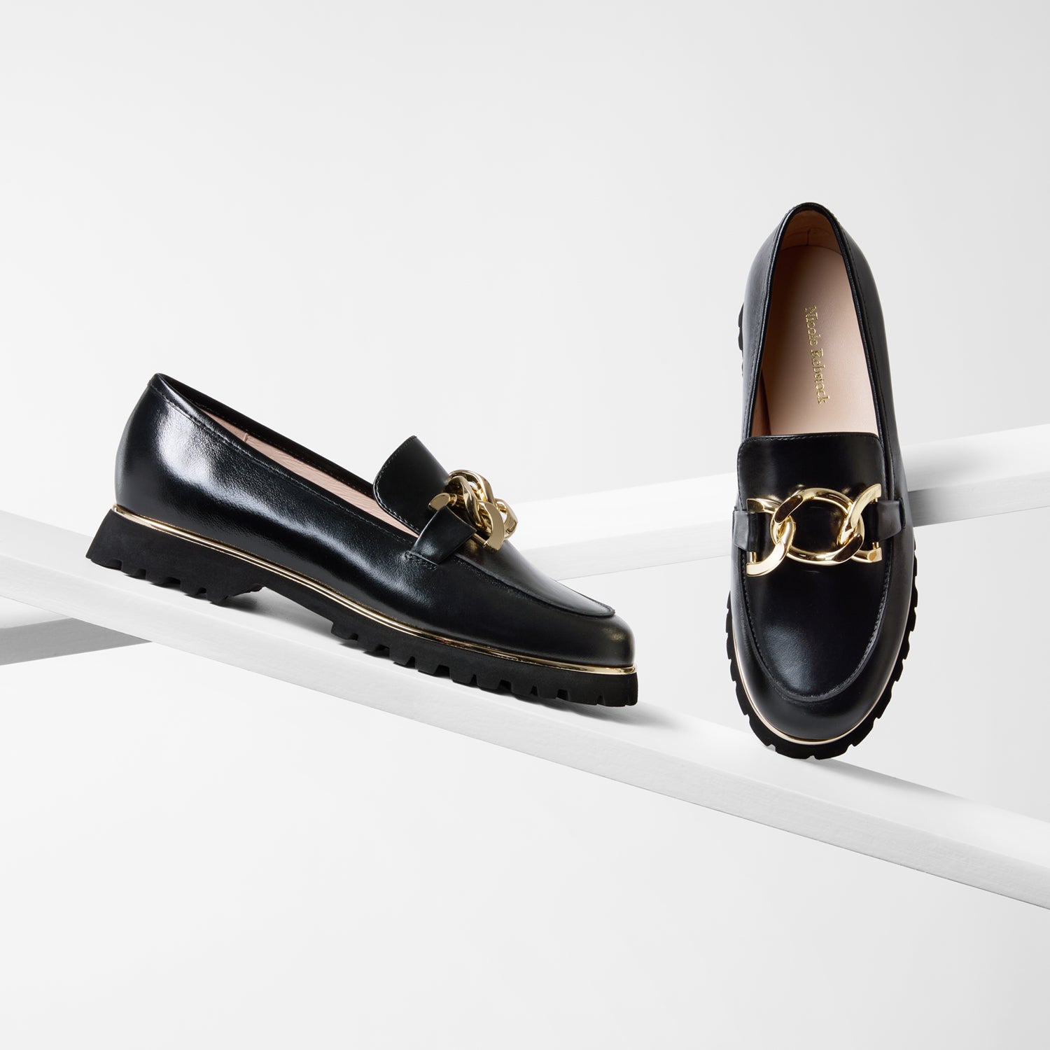 Black loafers with gold accents on a white surface