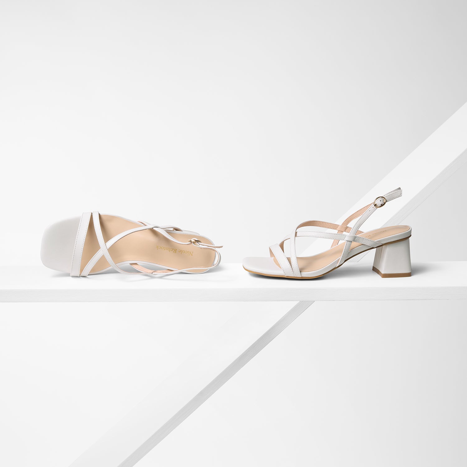 All angle view of strappy sandals called Ella. Off-white leather with gold buckle detail.