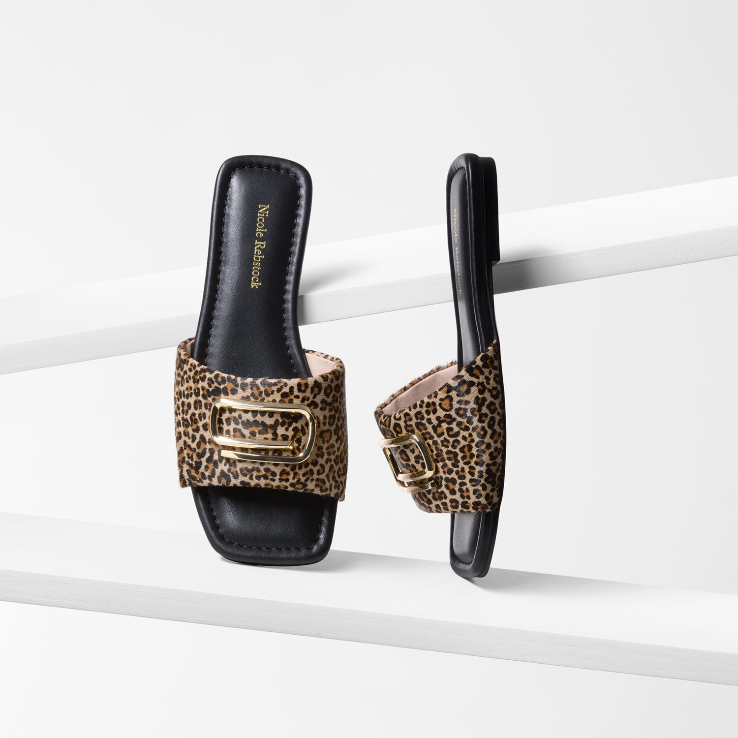Pair of leopard print slide sandals on a white background