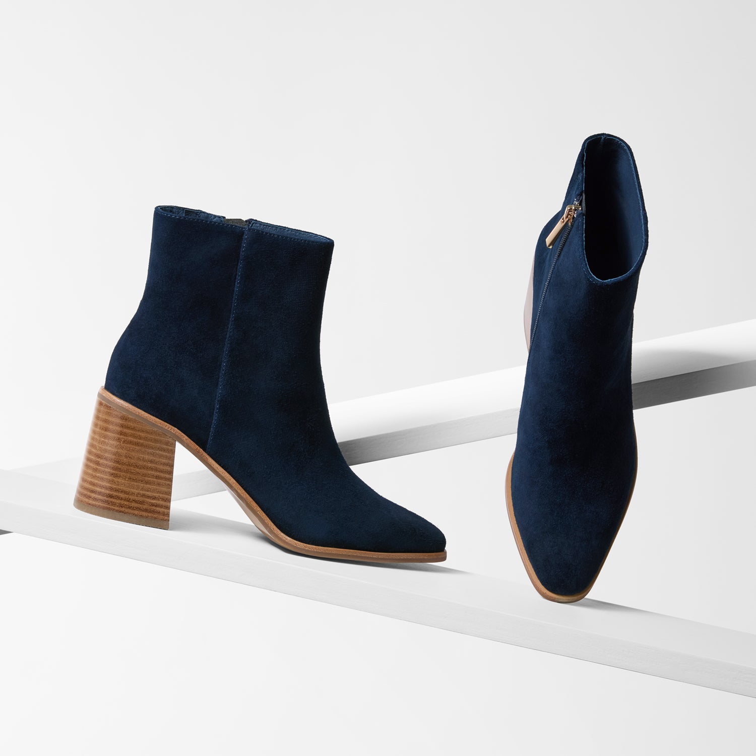 Pair of navy blue ankle boots with brown block heels on a white background