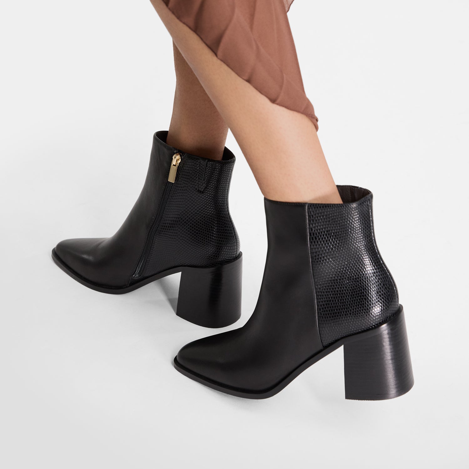 Close up of Nicole Rebstock black leather ankle boots with block heels on a white background worn by model.