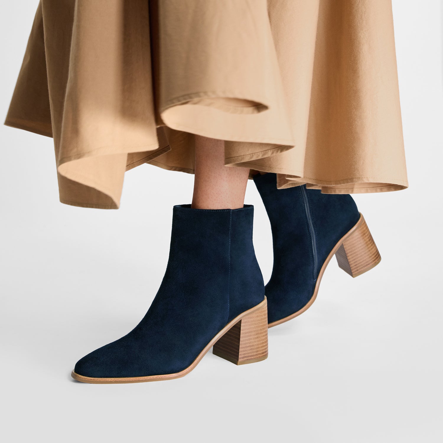 Blue suede ankle boots with wooden block heels worn by model on a light gray background