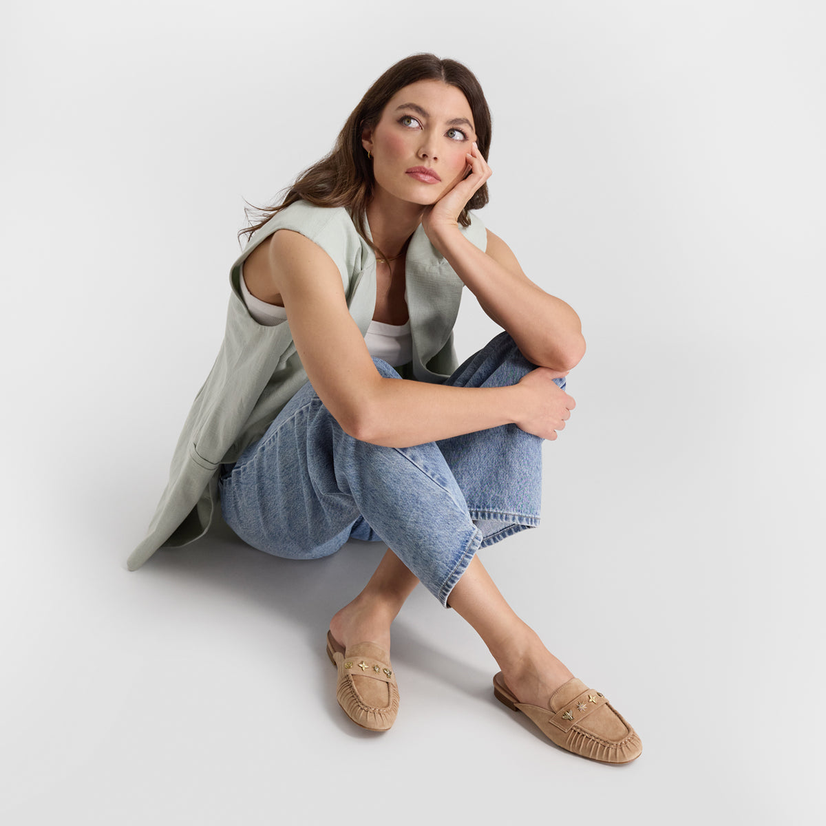 Model sitting wearing nude suede mule loafers