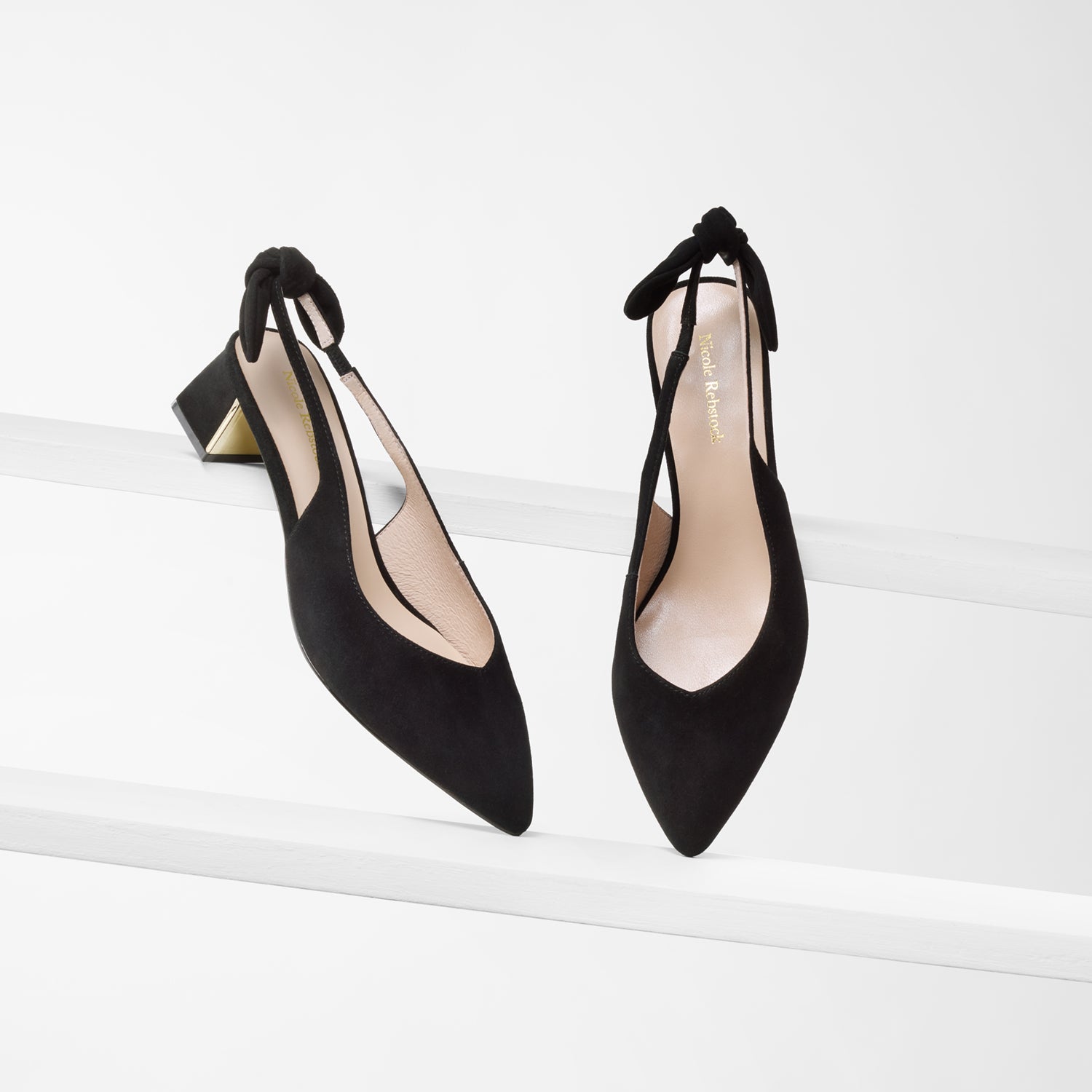 Hudson slingback in black suede shown from multiple angles. Pointed toe, gold mirror interior heel and black bow on back strap.
