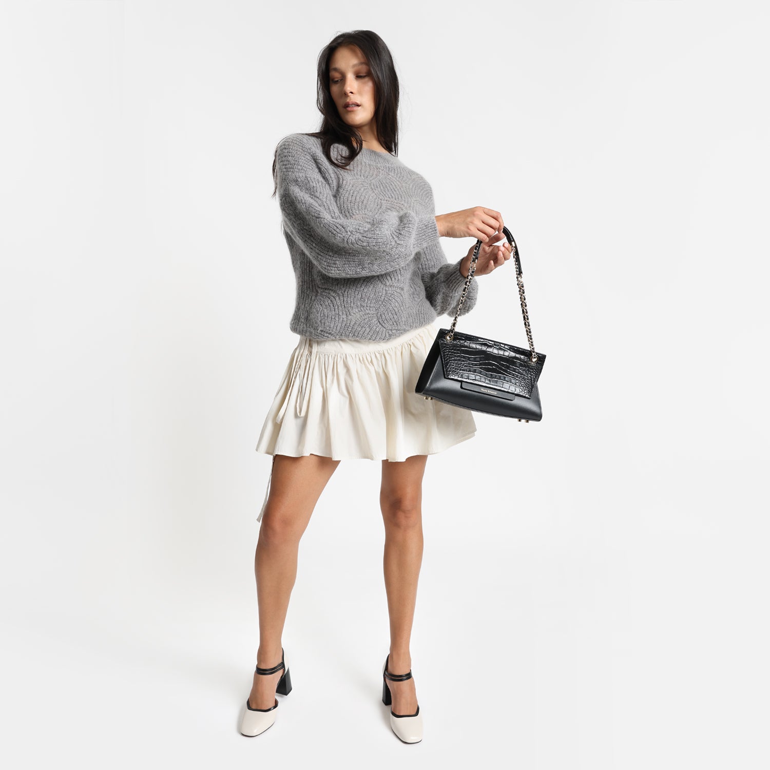 Heels named Jelico worn by model. They are ivory with a black heel and black trims with two slim Mary Jane straps.