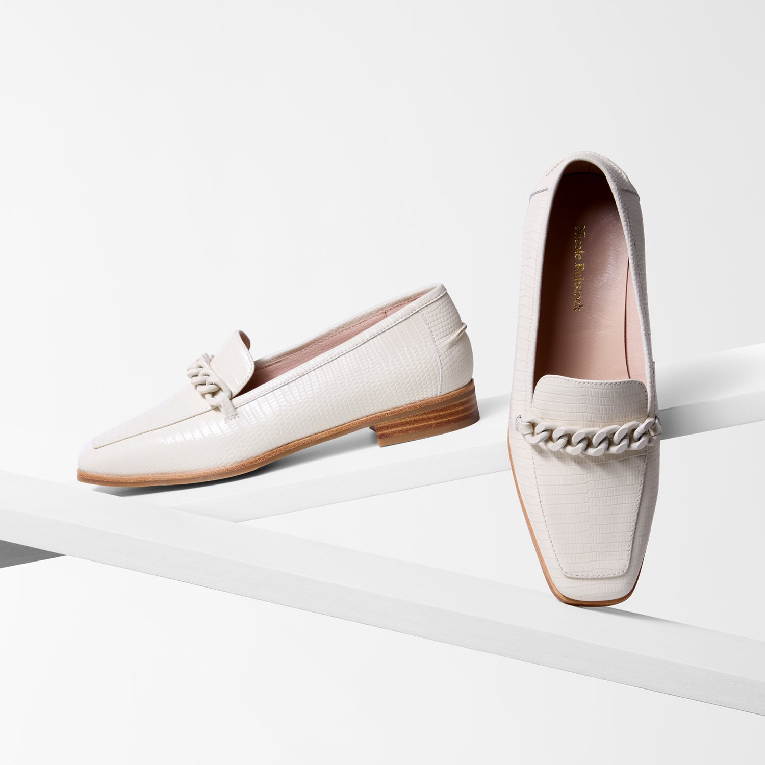 Pair of ivory loafers with retile embossed print with brown soles on a white background. Square toe. 2.5cm heel.