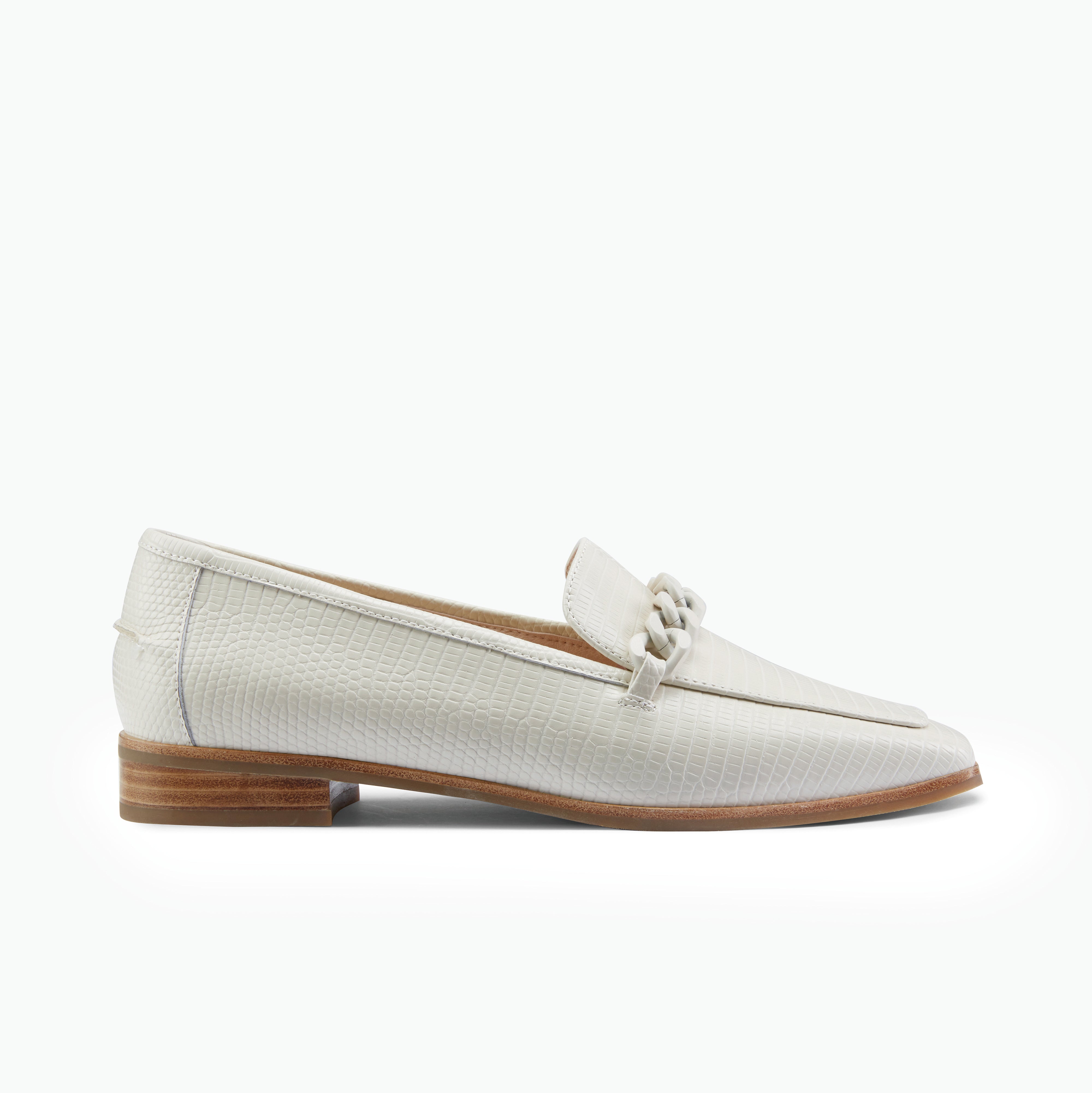Pair of ivory loafers with a brown sole on a white background