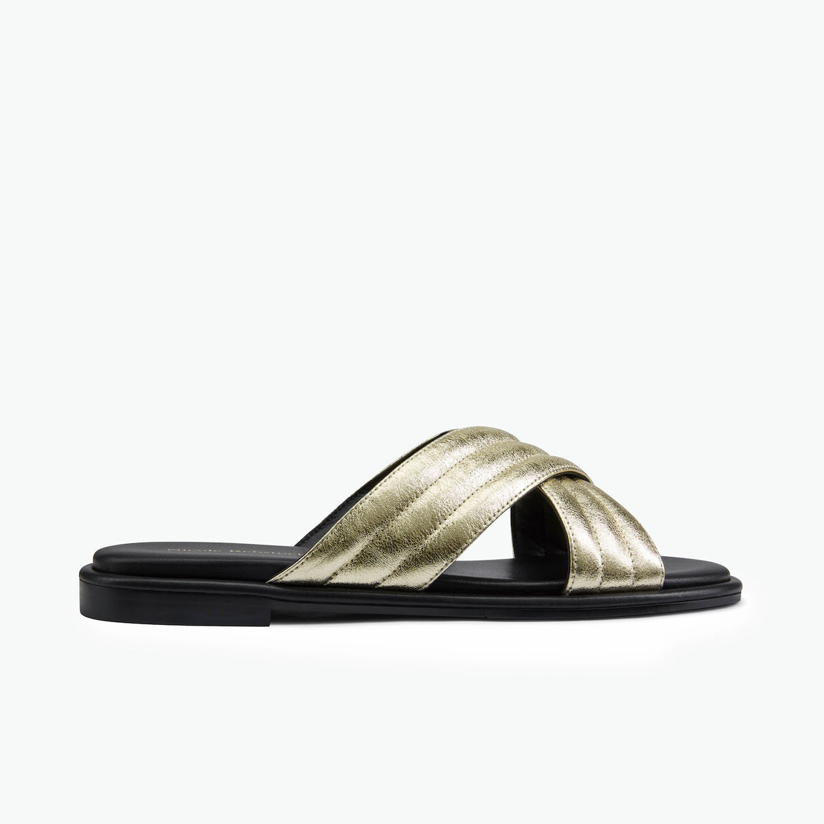 A single flat slide sandal with metallic gold crisscross straps and a black sole, shown in a side profile on a clean white background.