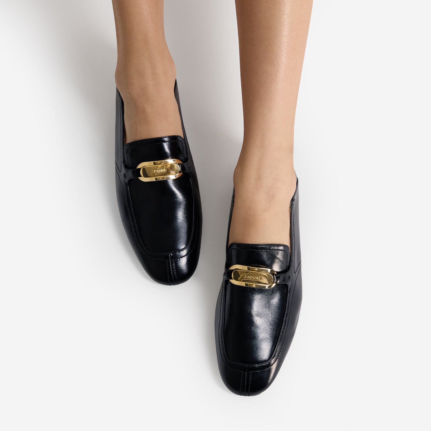 Black loafers with gold buckles on a white background