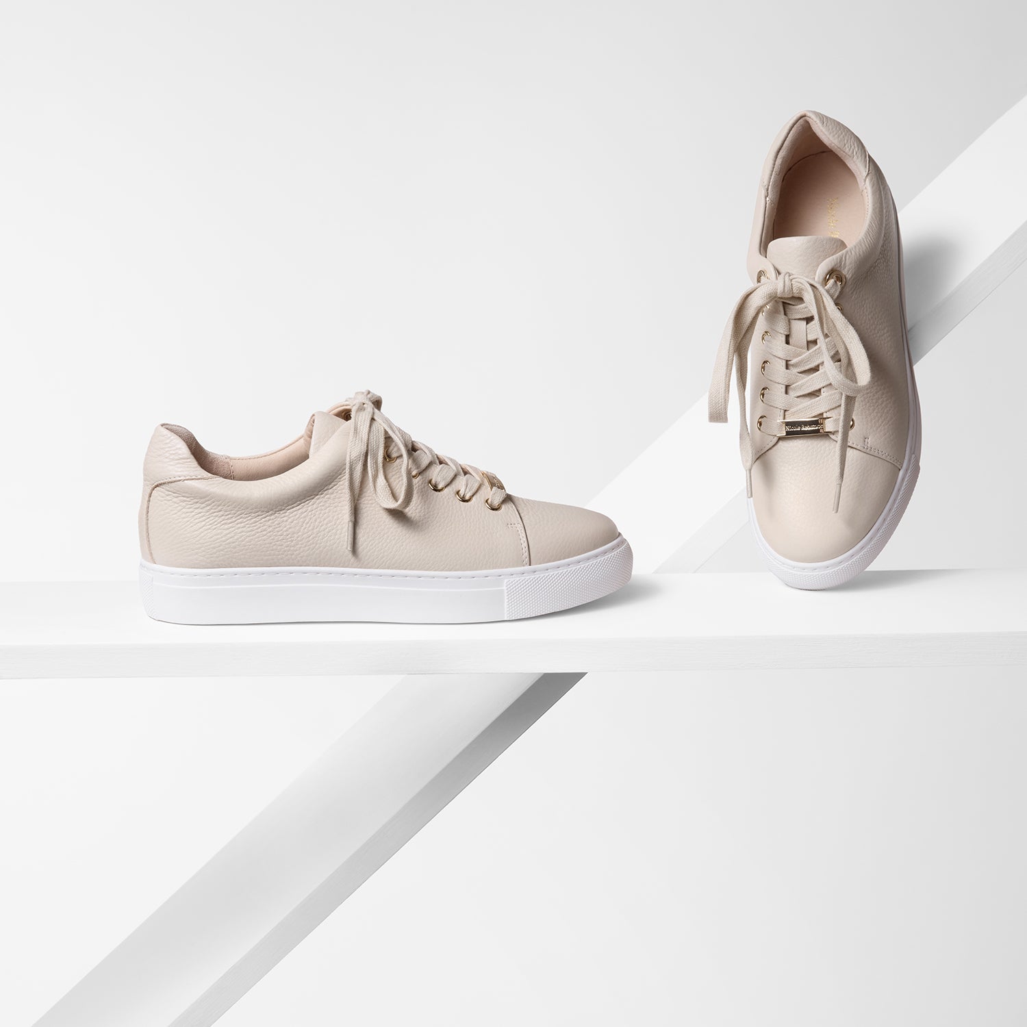 Sneaker called Mace on planks in all angles. The sneaker features blush pebble upper leather and gold hardware accents.