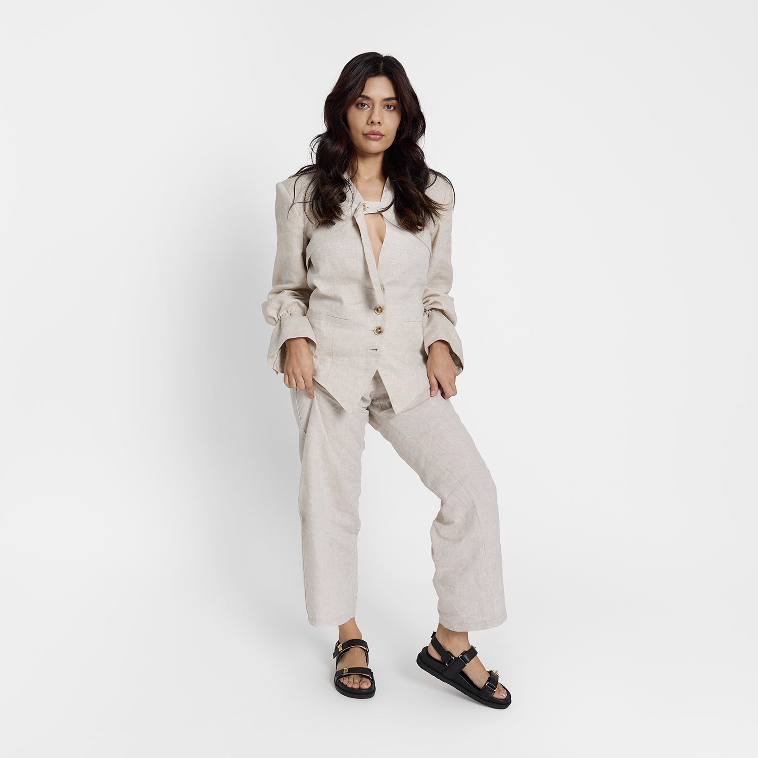 Model wearing Maine flat sandal in black with a Velcro strap and gold detail.