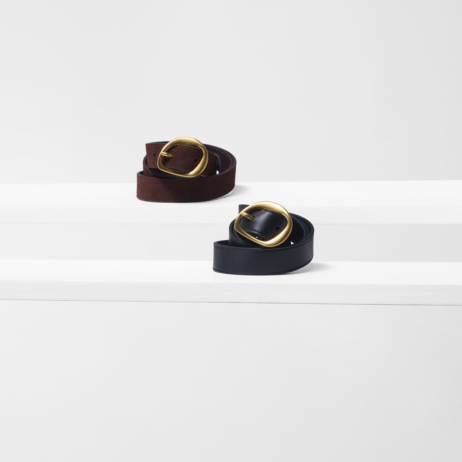 Two belts with gold buckles on a white background
