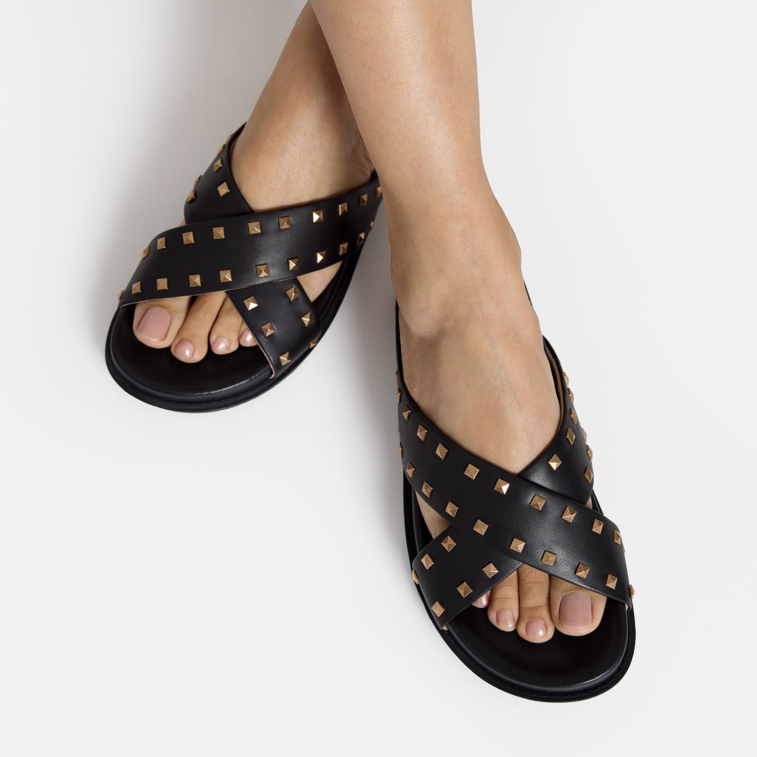 Close up view of model wearing Marlow slide sandal. Black leather with stud details.