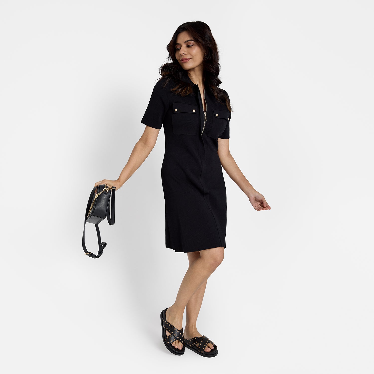 Woman showcasing black slide sandal called Marlow from all angles. They have a cross strap and rose gold studs.