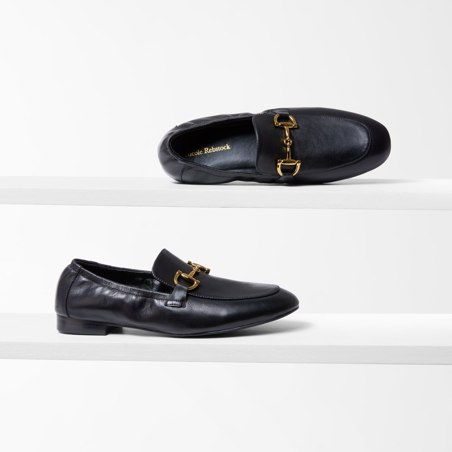 Black leather loafers with gold buckles and a 2cm heel on a white background.