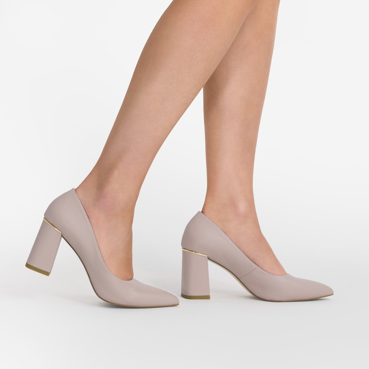 A pair of women's block-heel pumps in a light taupe-beige color, shown on a model's feet against a clean white studio background. 7.5cm heel.