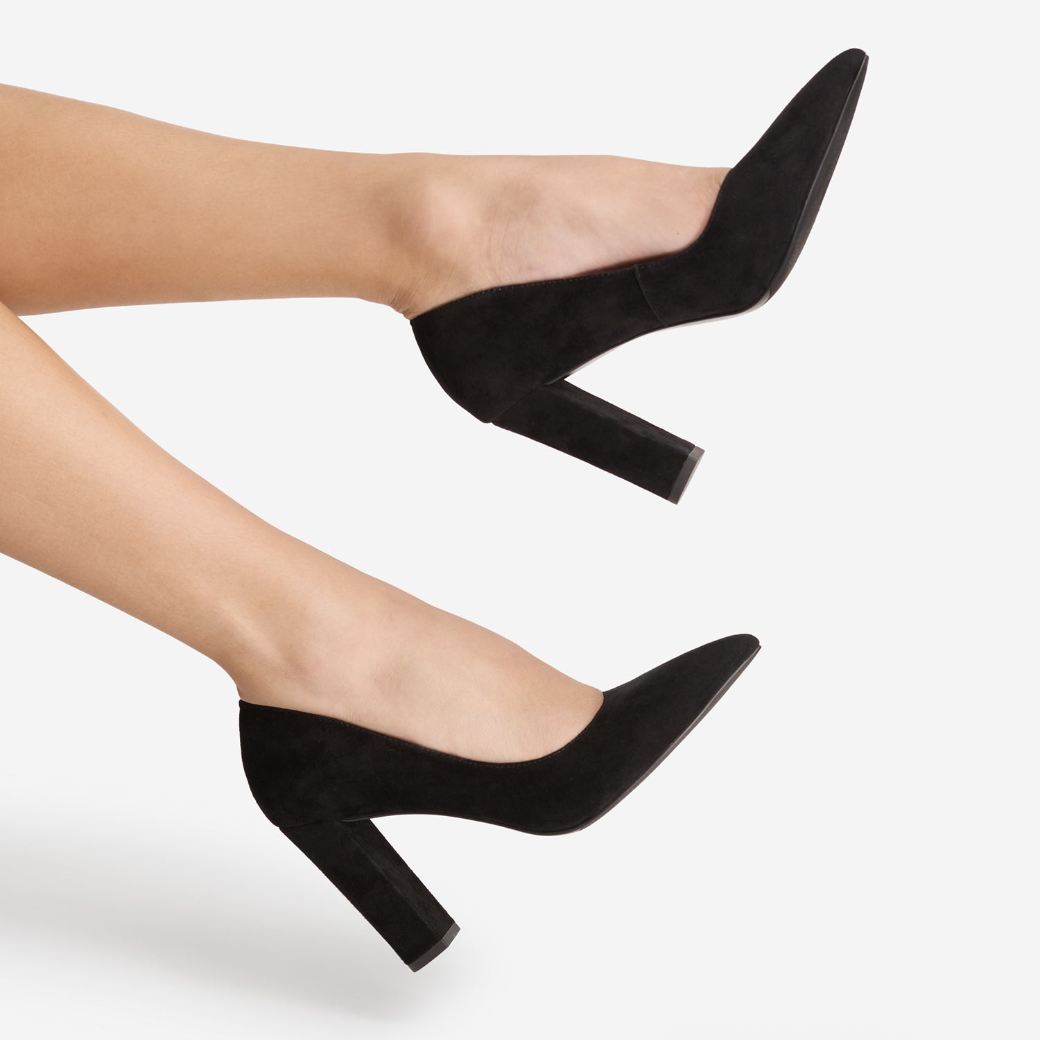 A pair of black pointed-toe high heels by Nicole Rebstock with block heels, shown on a model's feet against a light gray background.