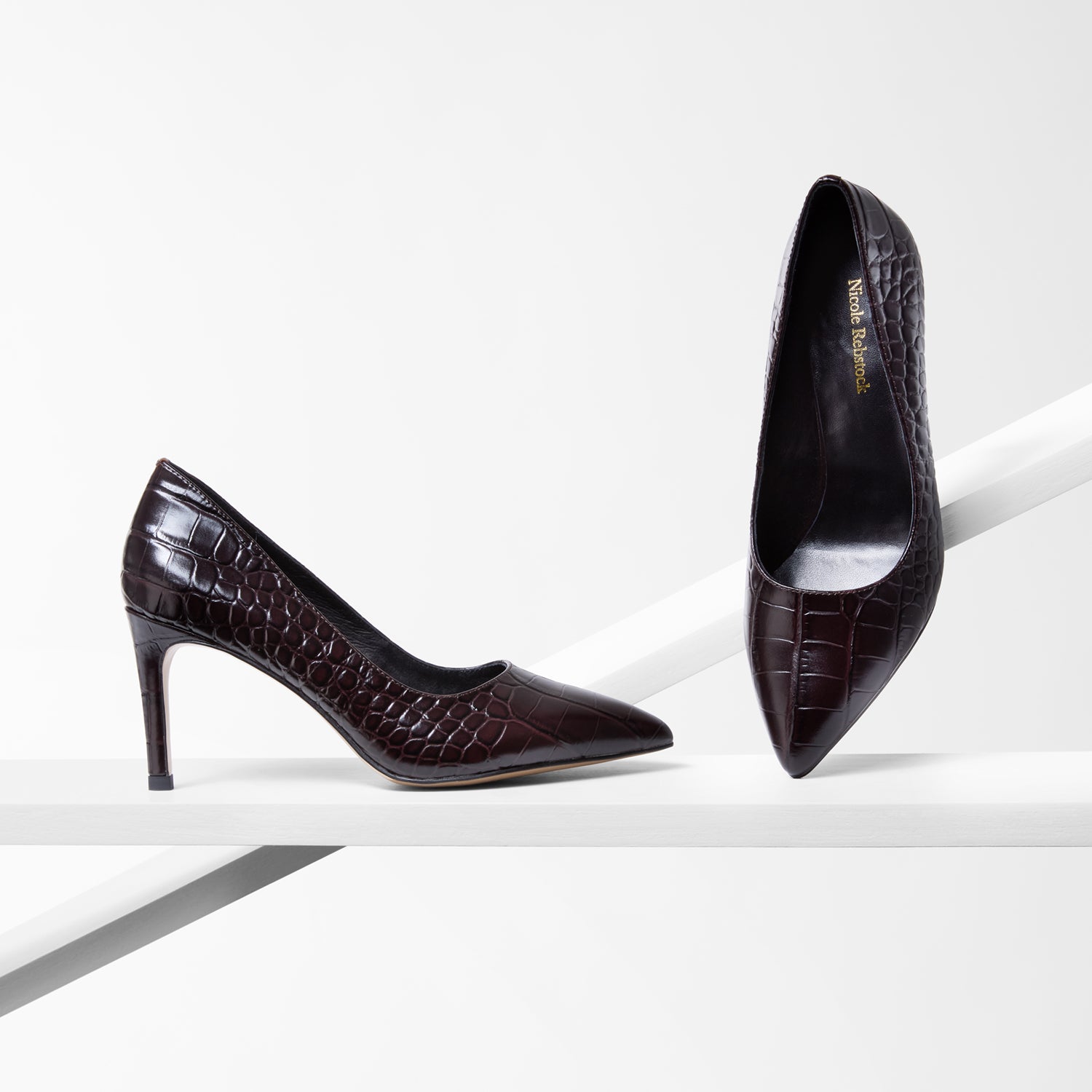 Pair of brown high-heeled shoes with crocodile texture on a white background
