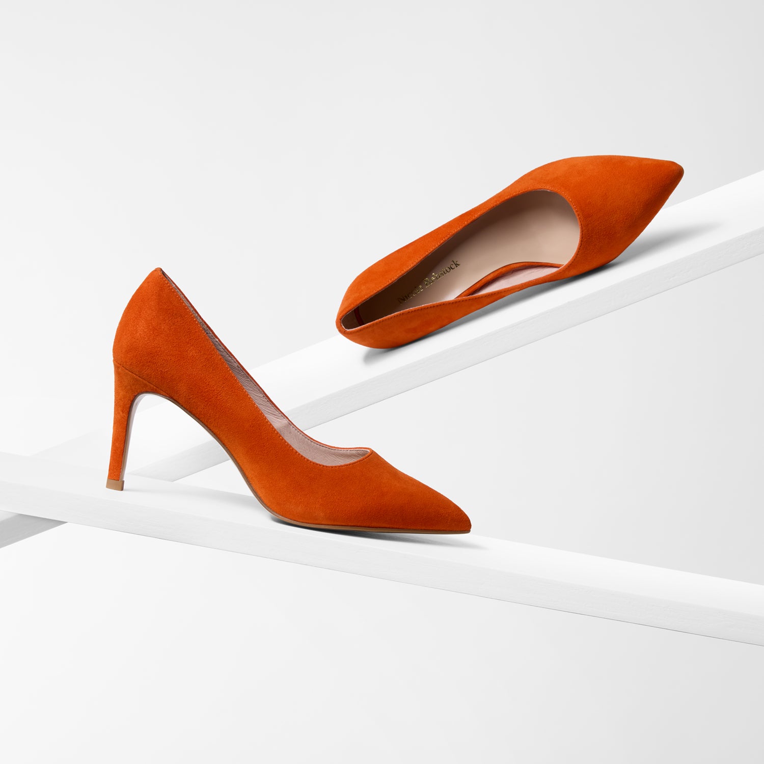 Orange high-heeled shoes on a white background. Pointed toe and slim heel.