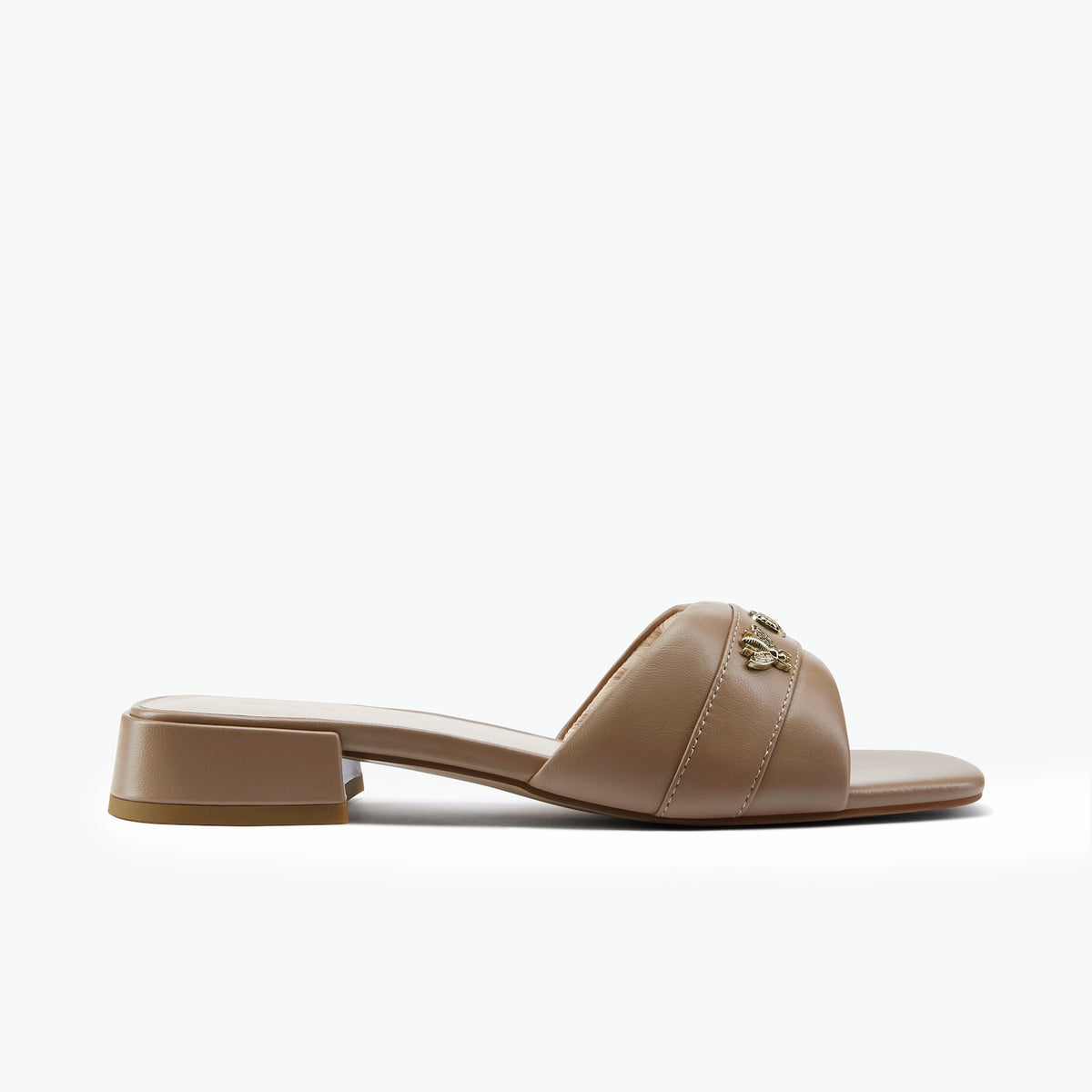 A taupe-brown leather slide sandal with a low block heel and a small gold-tone decorative emblem on the strap, shown in profile against a clean white background.