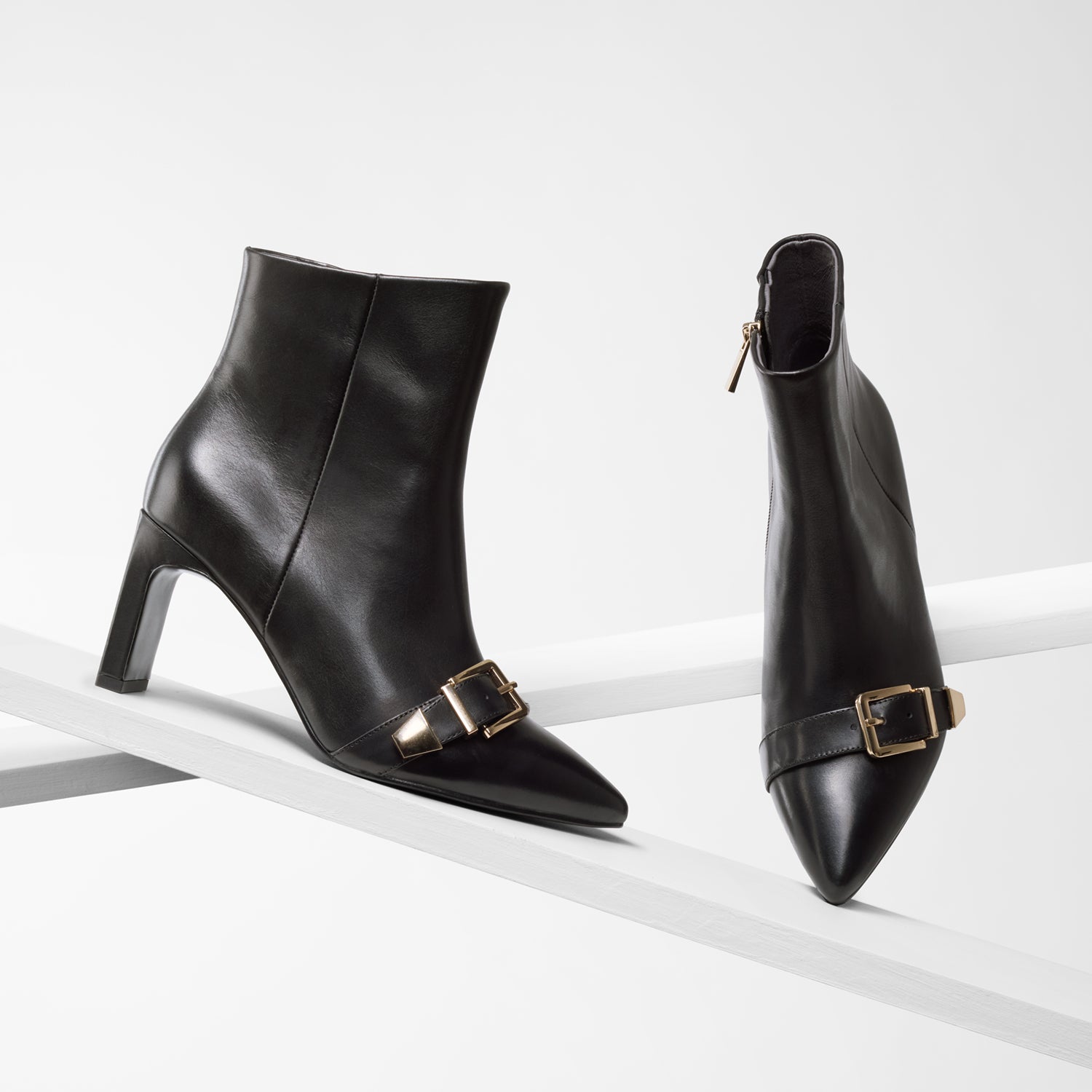 Rome black ankle boot shown from various angles. The boots features rectangular heel, pointed toe and gold metal buckles on toes.