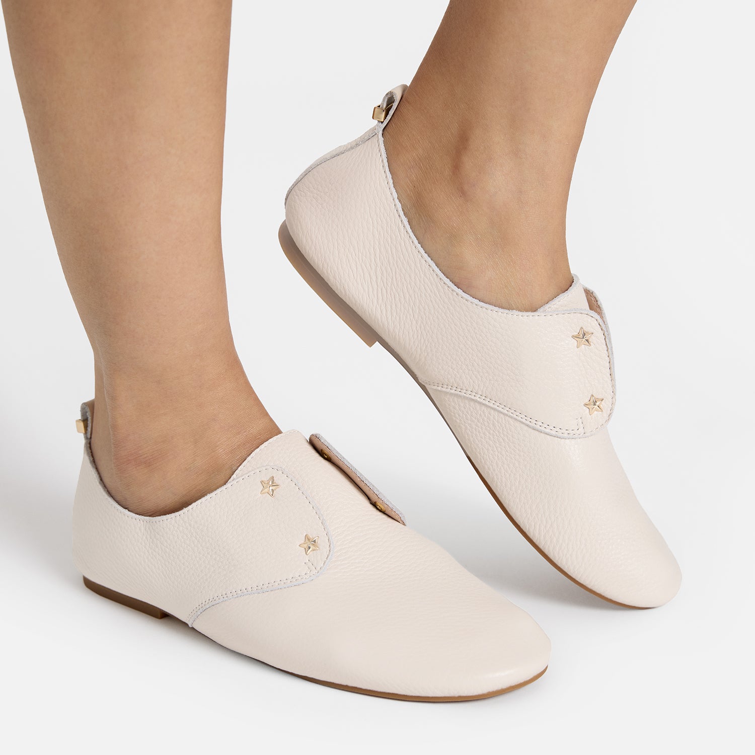 Beige loafers worn by a person on a white background