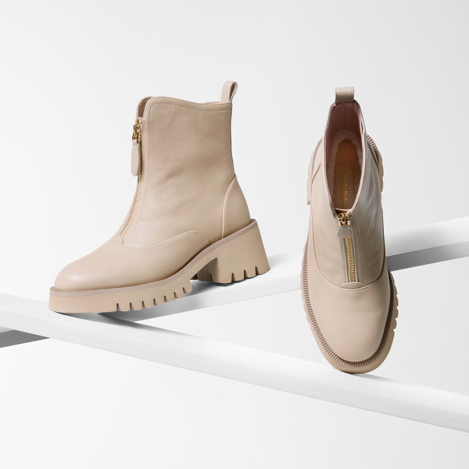 Nude ankle boots with zippers on front on a white background. Low heel. Chunky thread.