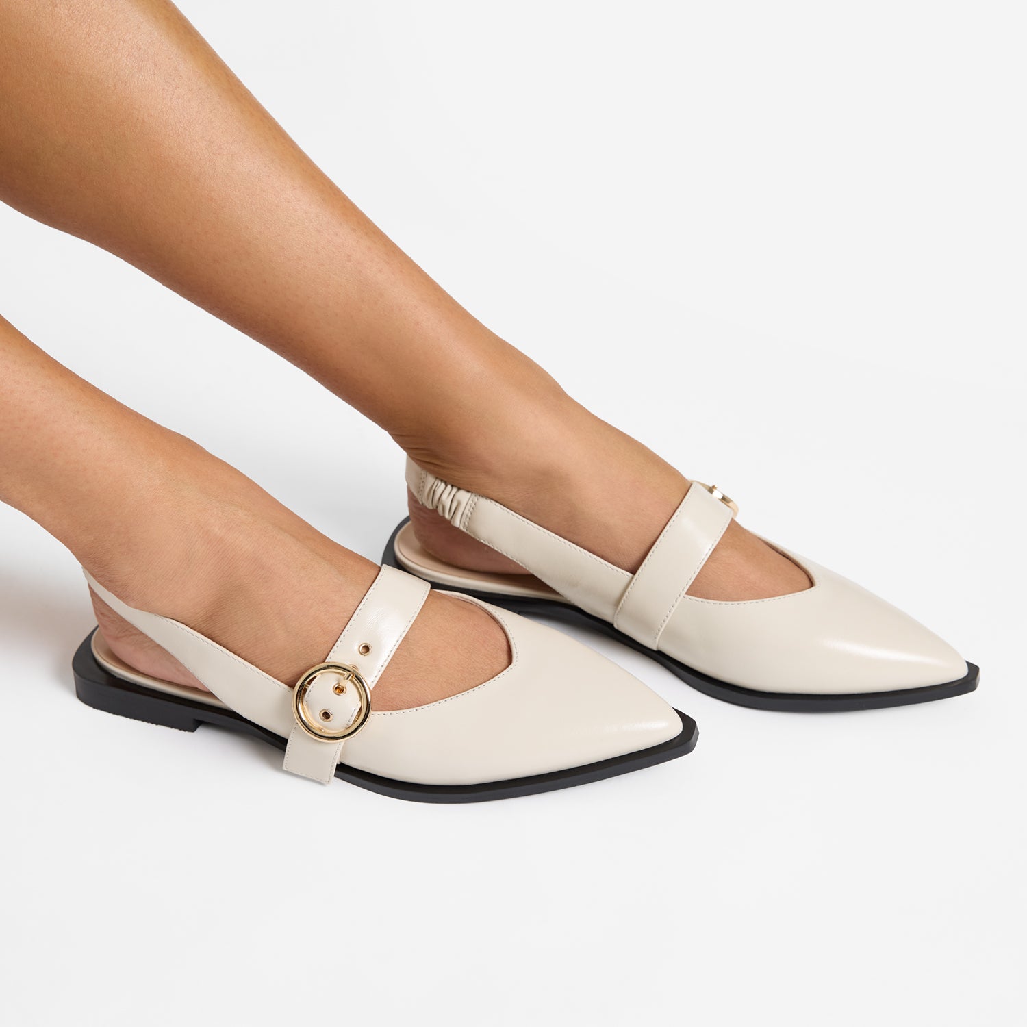 Valencia ivory oiled leather slingback with pointed toe, black sole and gold buckle shown on women's feet.