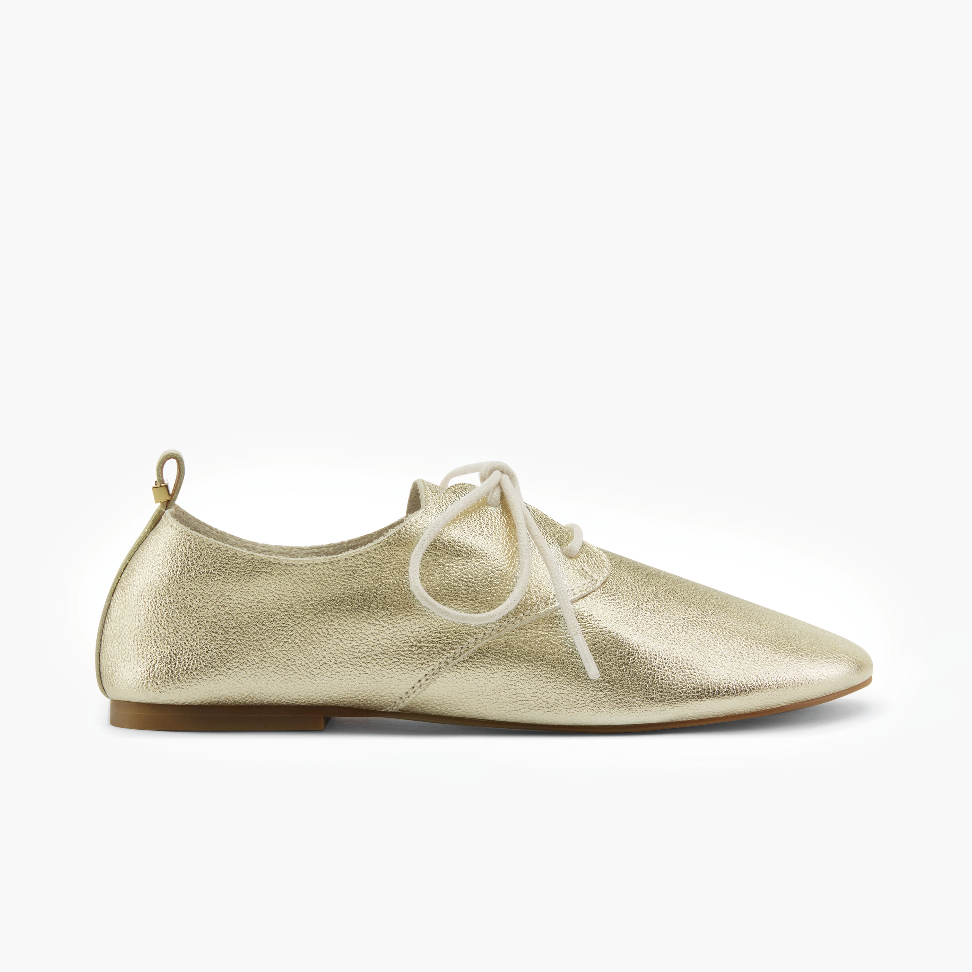 Soft gold leather shoe with white laces on a white background by Nicole Rebstock.