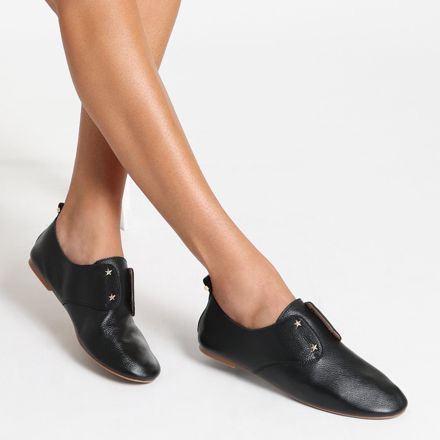 Woman wears black Xeno Flat Shoe. Casual pull-on style.