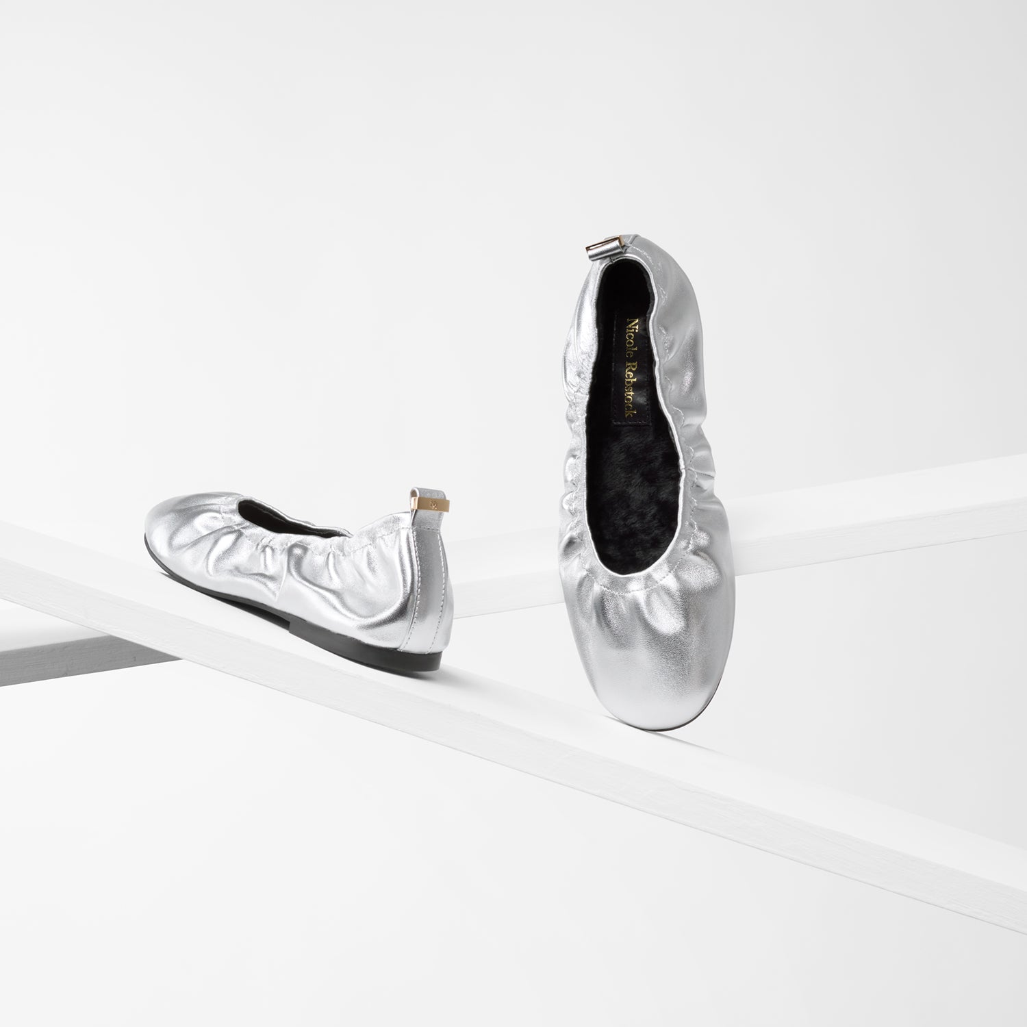 Pair of silver scrunchie ballet flats with black wool insoles.