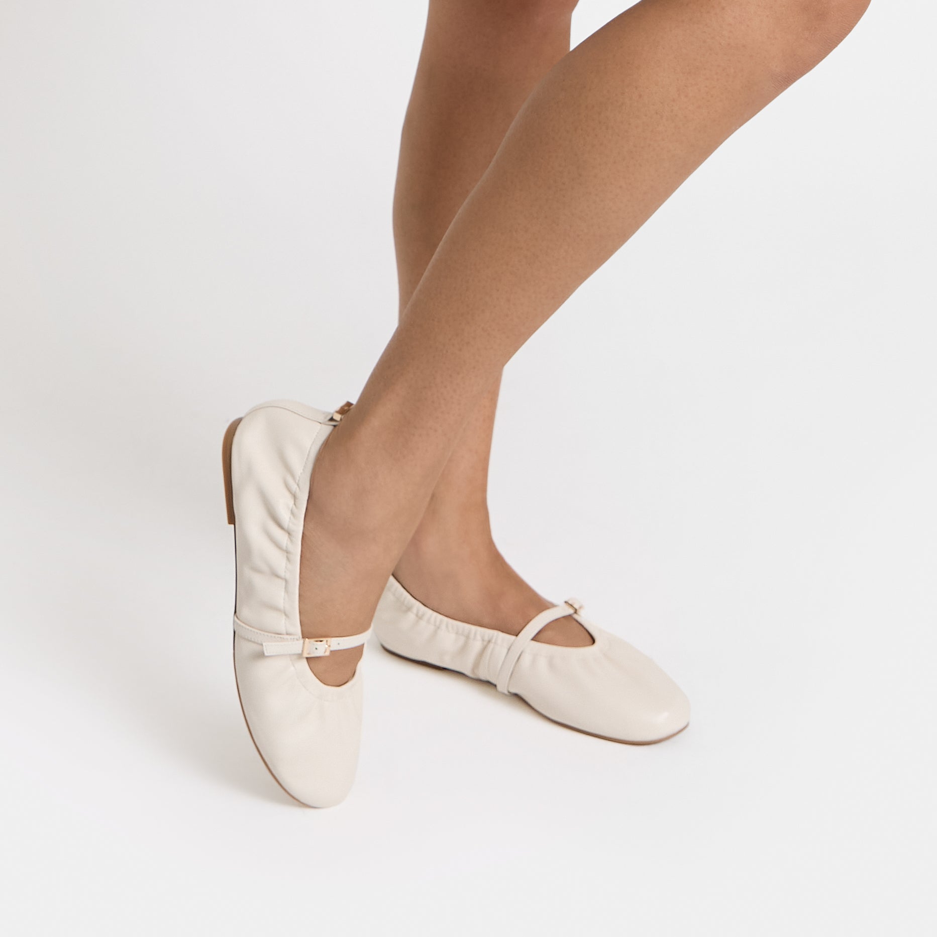 Close up of Xyla ivory scrunchie ballet flats. Worn by model. Mary Jane Strap with gold buckle detailing.