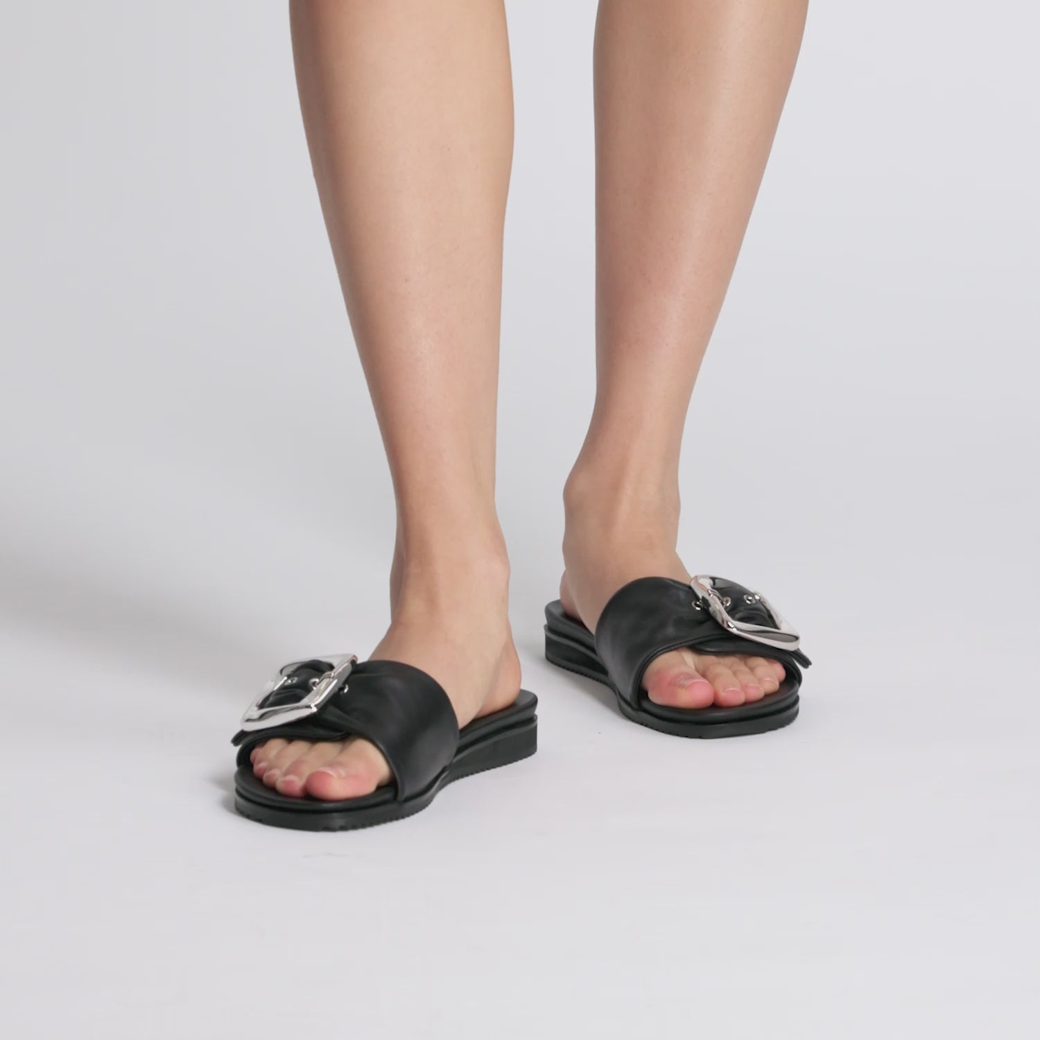 Black slide sandals with silver buckle by Nicole Rebstock