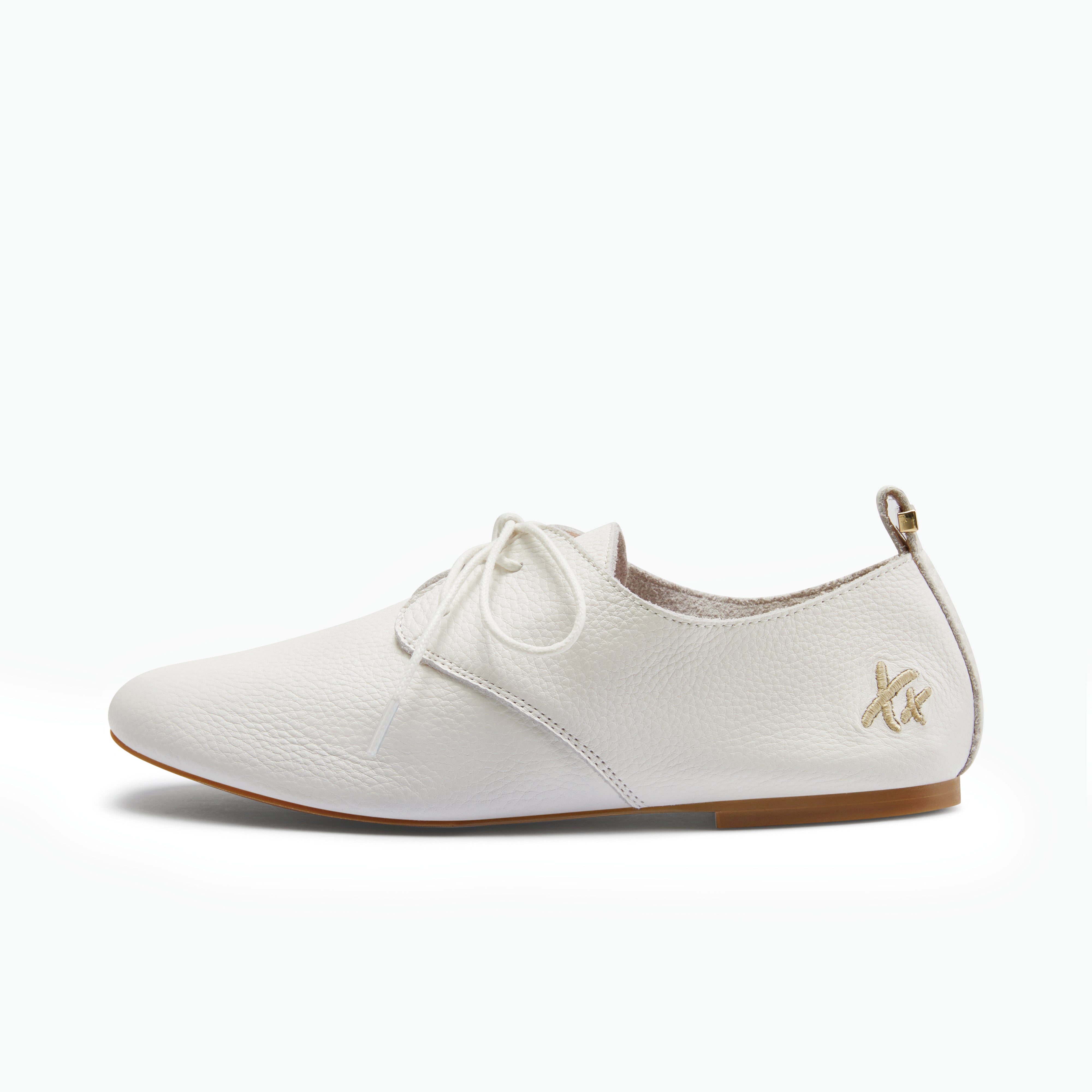 A white pebbled leather lace-up shoe with a small gold logo on the heel, shown in a side profile against a clean white background.