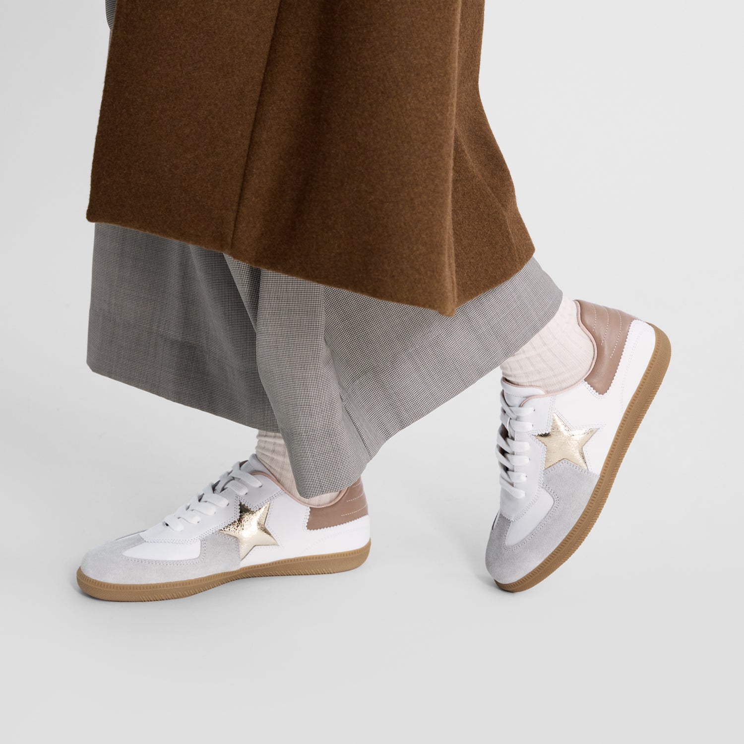 White sneakers with gold stars worn by model.