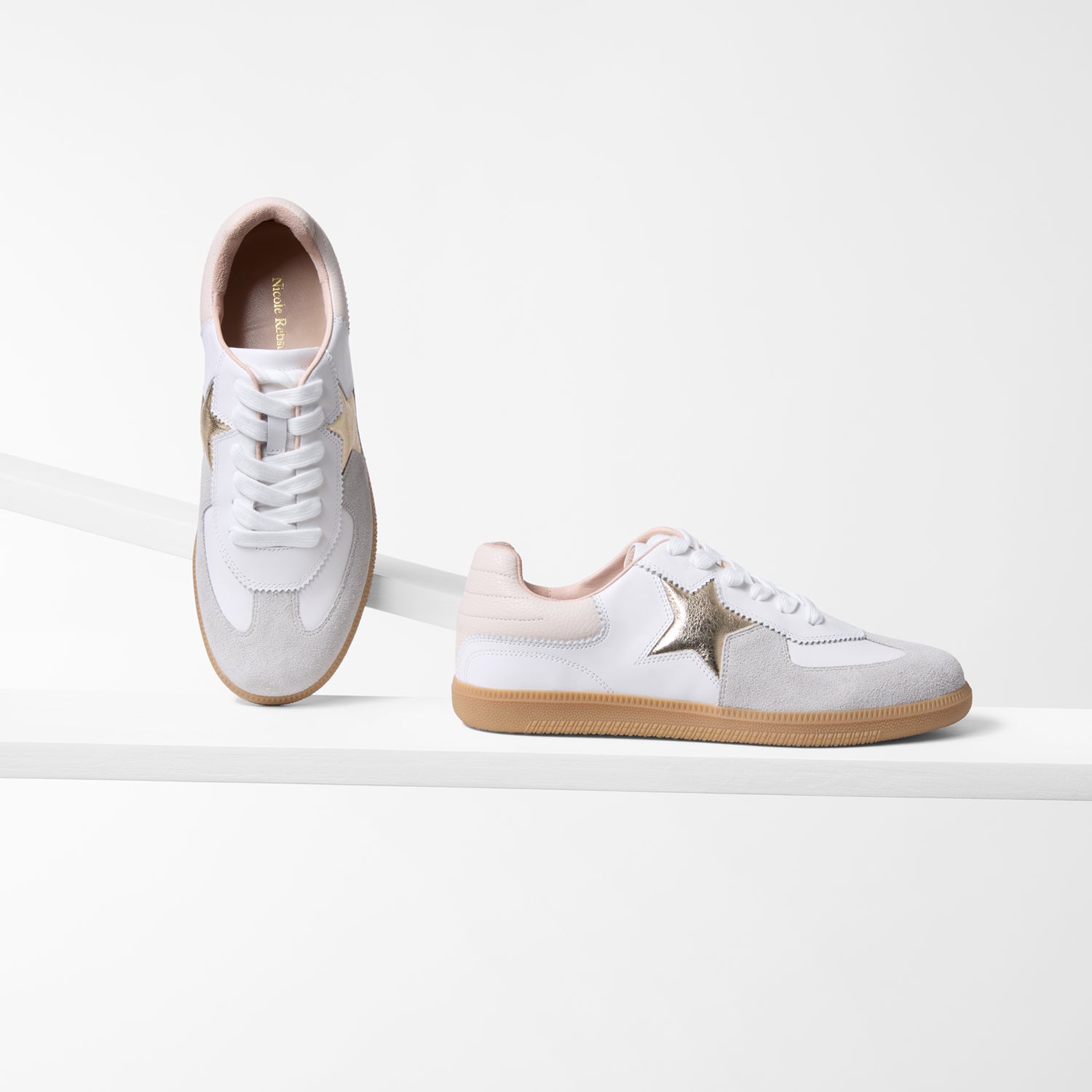 White sneakers with gold and blush accents on a white background