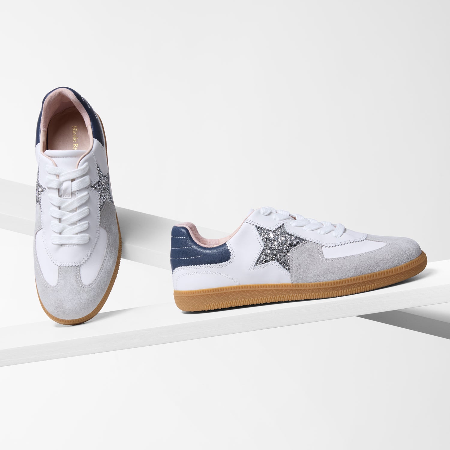 Pair of white leather sneakers with grey suede toe and navy heel on a white background.
