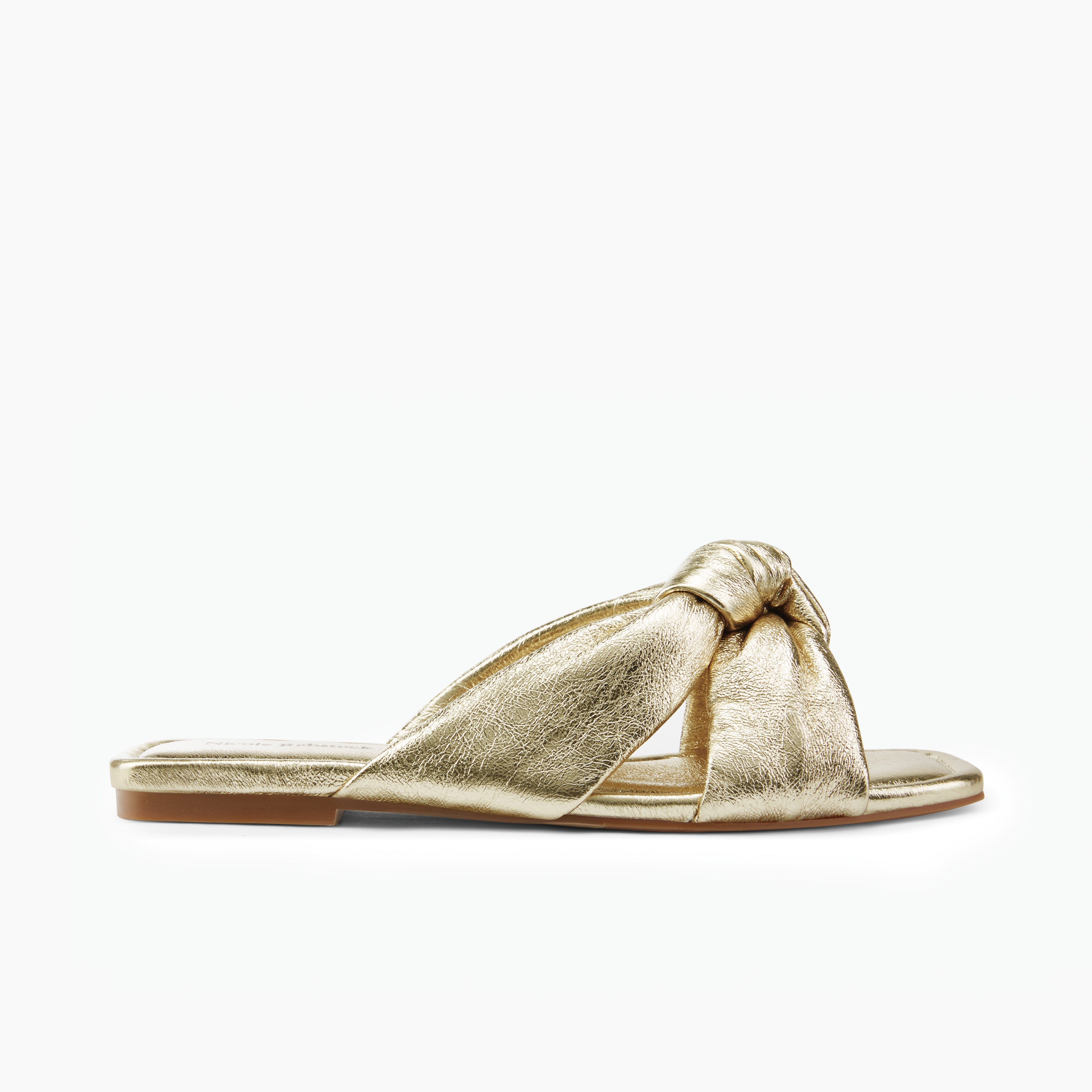 Gold sandal with a knot design on a white background